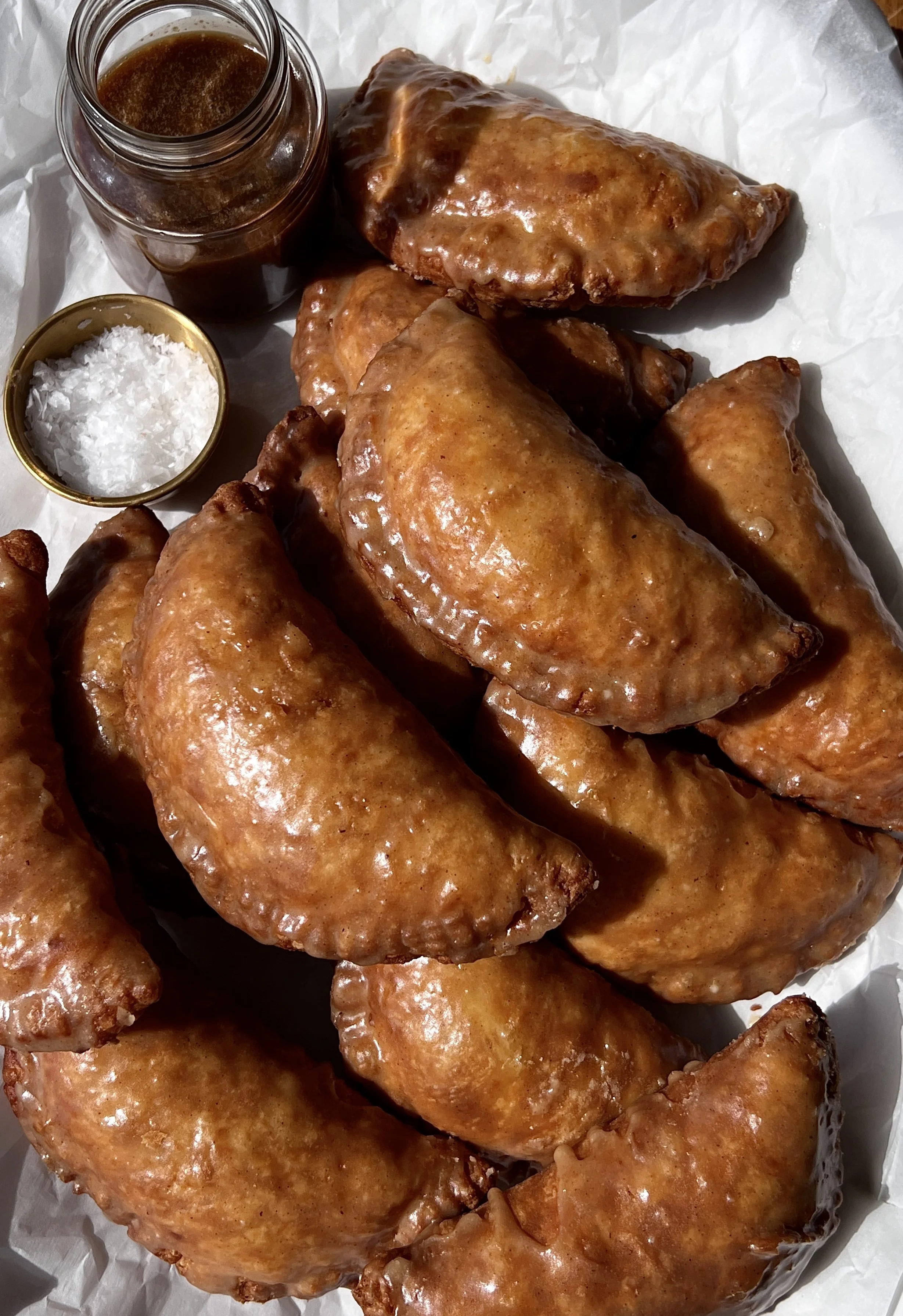 Fried apple hand pies with a golden flaky buttery crust finished with a brown butter maple vanilla bean glaze melting over the top.