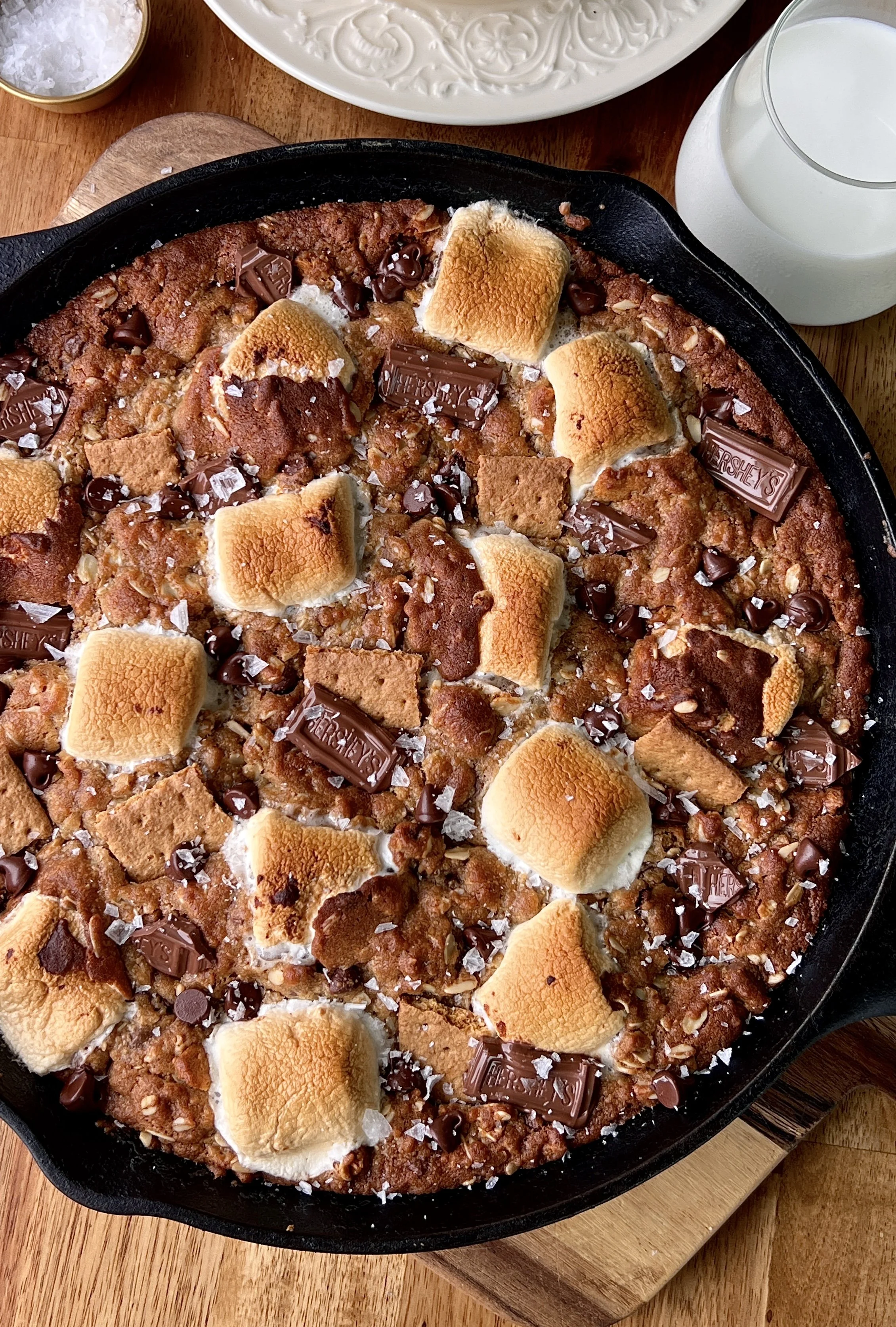 Peanut butter s'mores oatmeal cookie skillet with melty chocolate, gooey toasted marshmallows, and crushed graham crackers served warm with a scoop of vanilla ice cream and flaky sea salt.