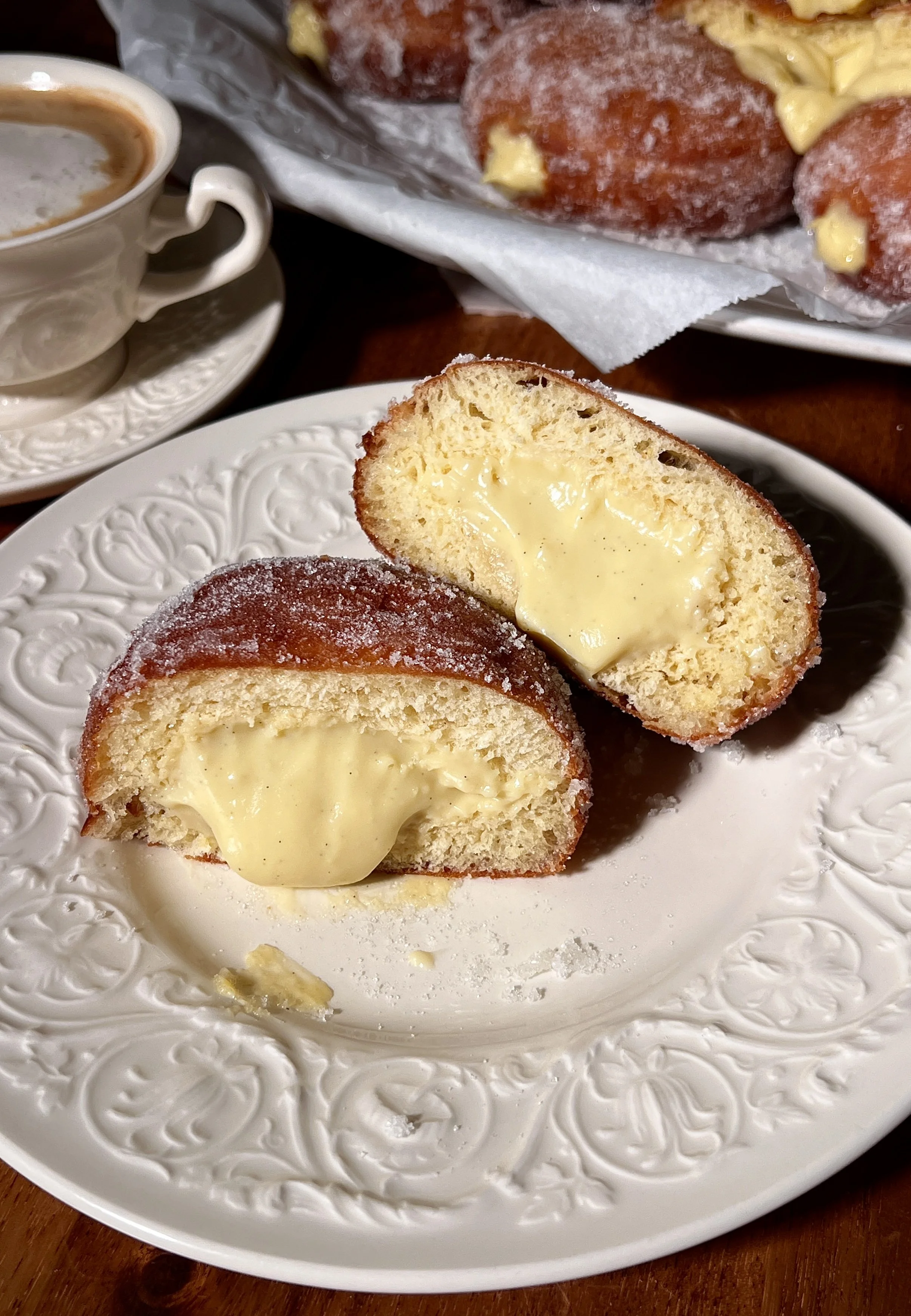 Warm vanilla bean coconut cream bomboloni rolled in sugar and served with a cup of coffee.