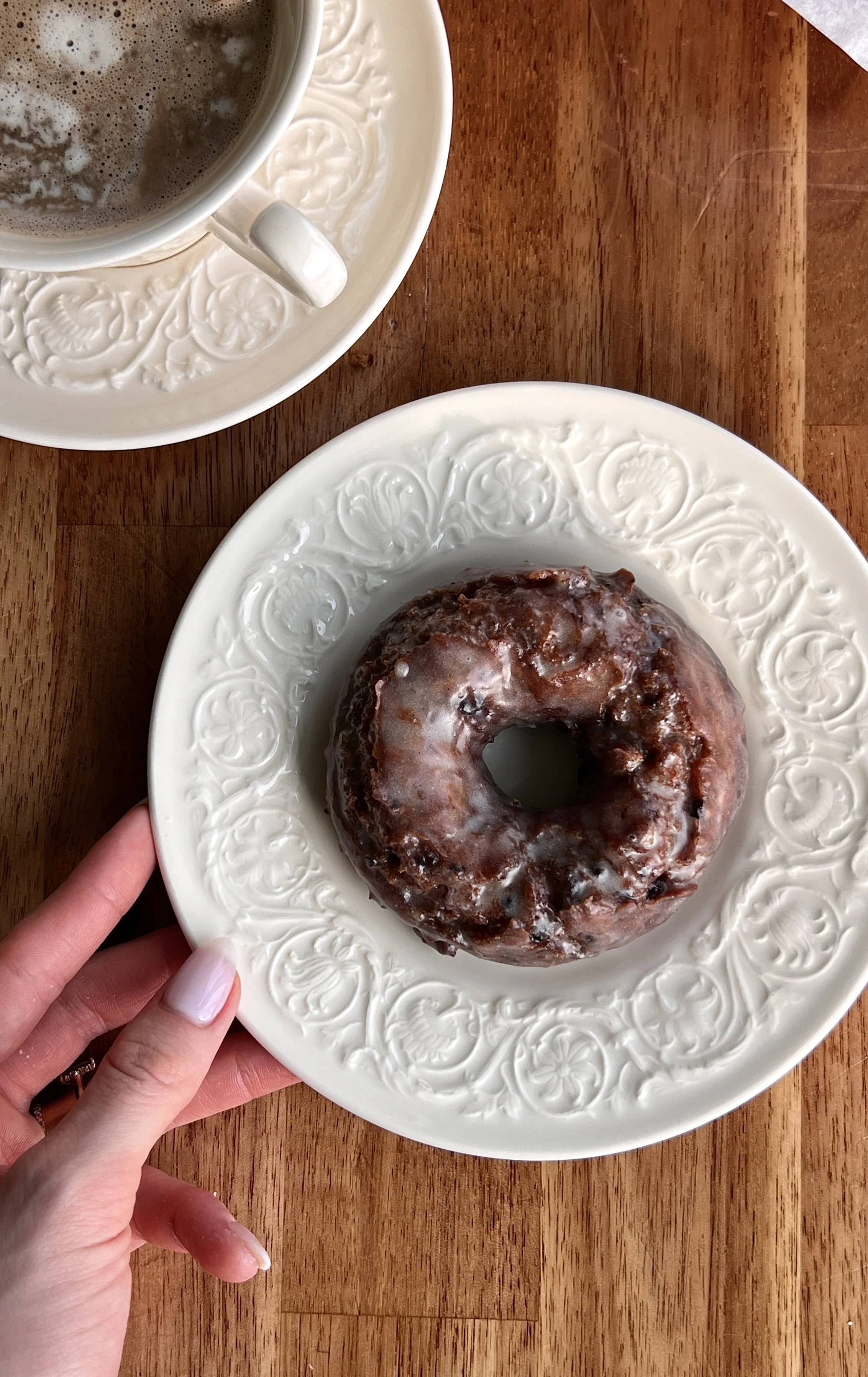Warm blueberry cake donuts with vanilla glaze served with a hot cup of coffee.