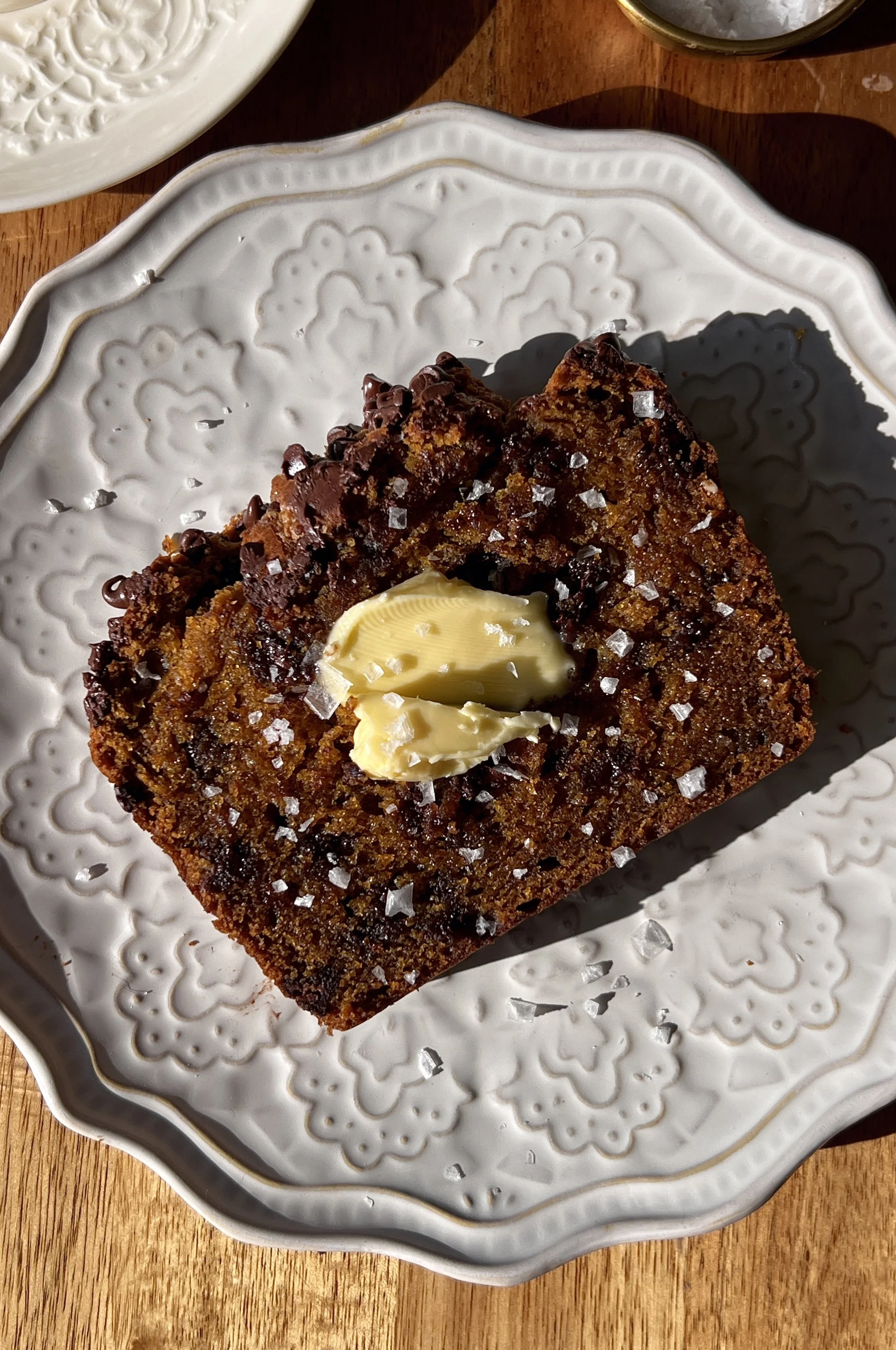 Soft and tender brown butter chocolate chip pumpkin bread with a perfectly golden and slightly crisp exterior and melty chocolate chips throughout served warm with a pat of butter a sprinkle of flaky sea salt and a hot cup of coffee.