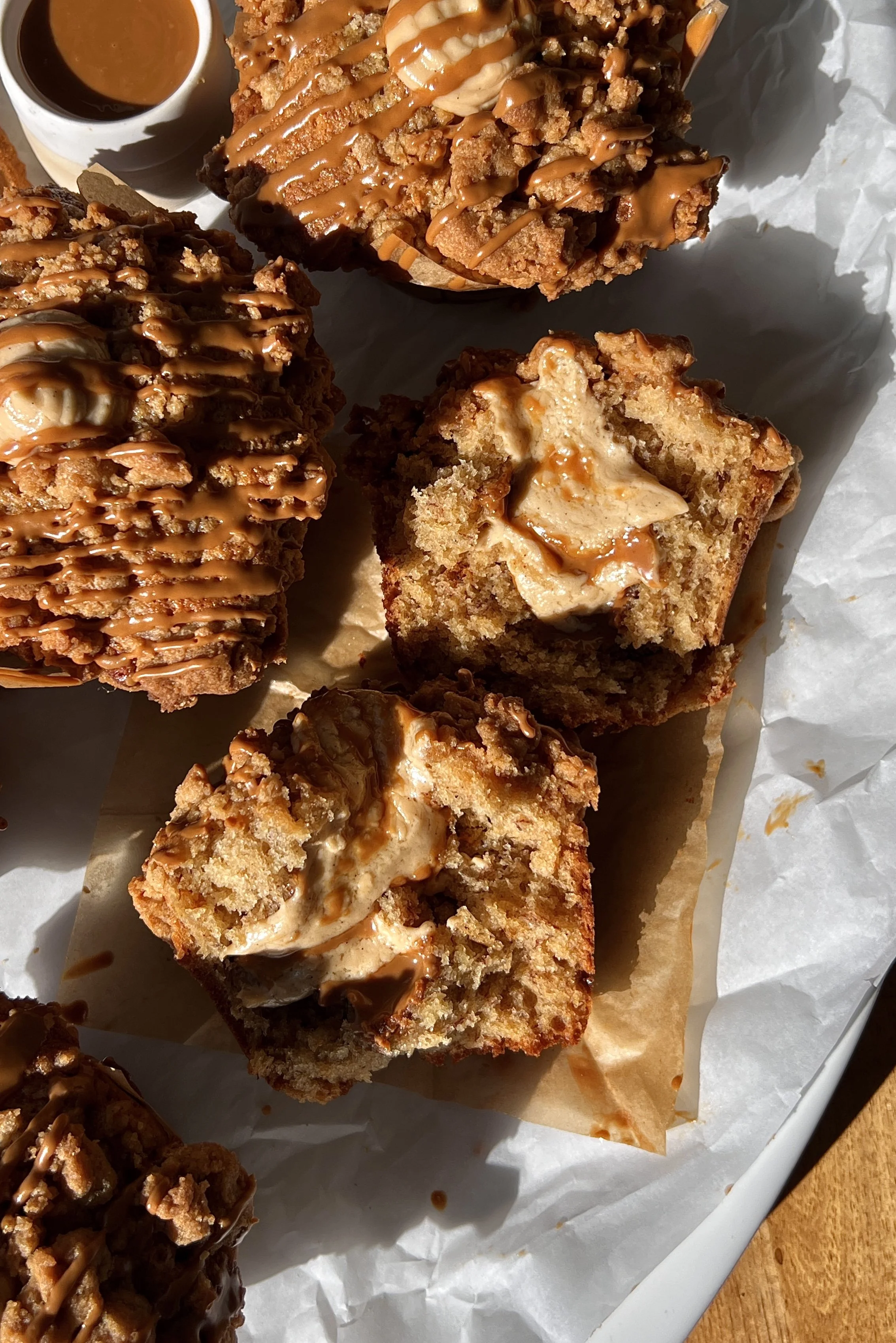 Close-up of a bakery-style banana Biscoff muffin showing the soft fluffy tender banana crumb with a rich Biscoff cream cheese filling and Biscoff cookie butter inside and a golden Biscoff streusel topping.