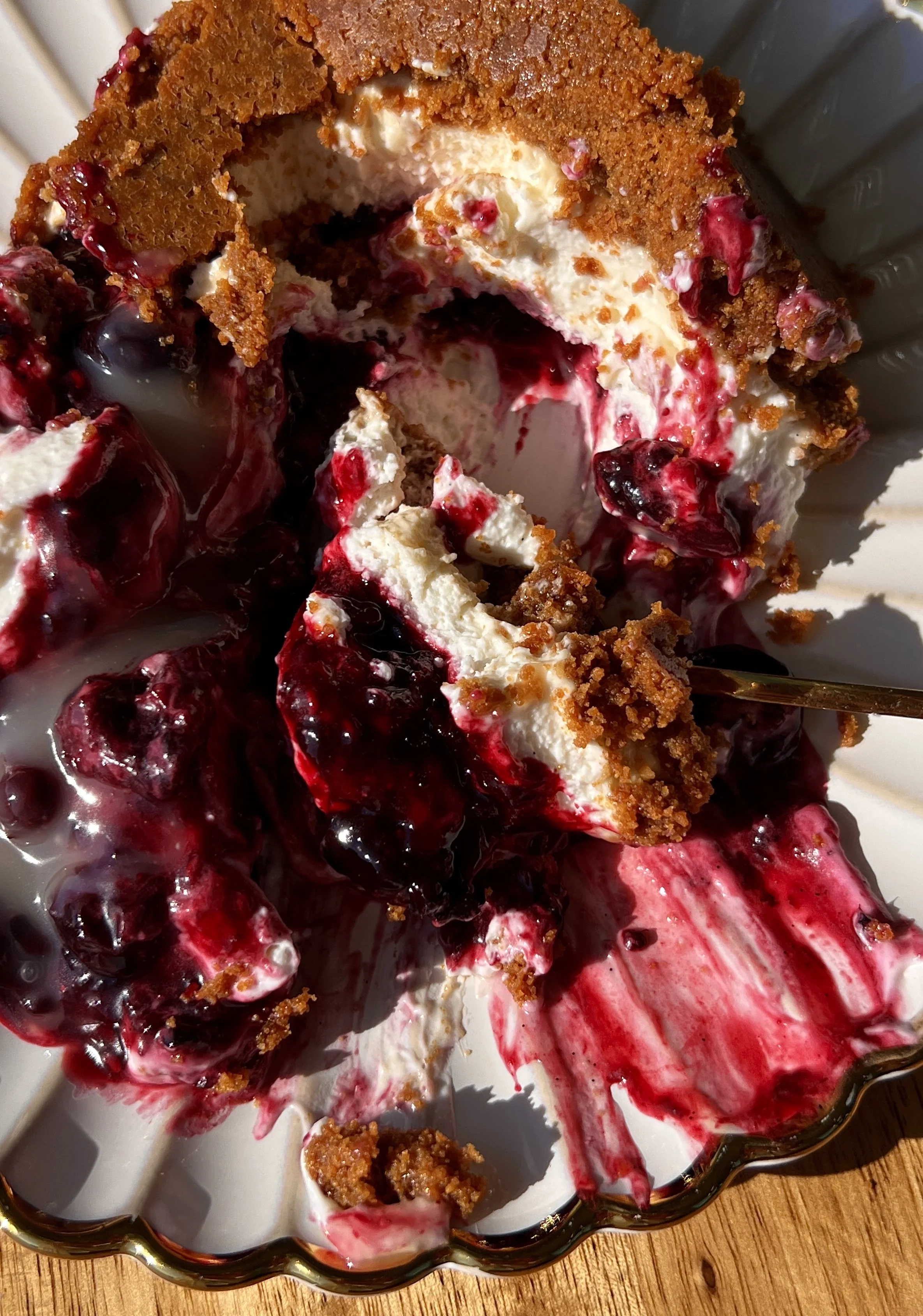 Upside down triple berry no-bake cheesecake with a perfectly crunchy Biscoff cookie crust inverted to serve and finished with a dollop of bright lemon curd on top.