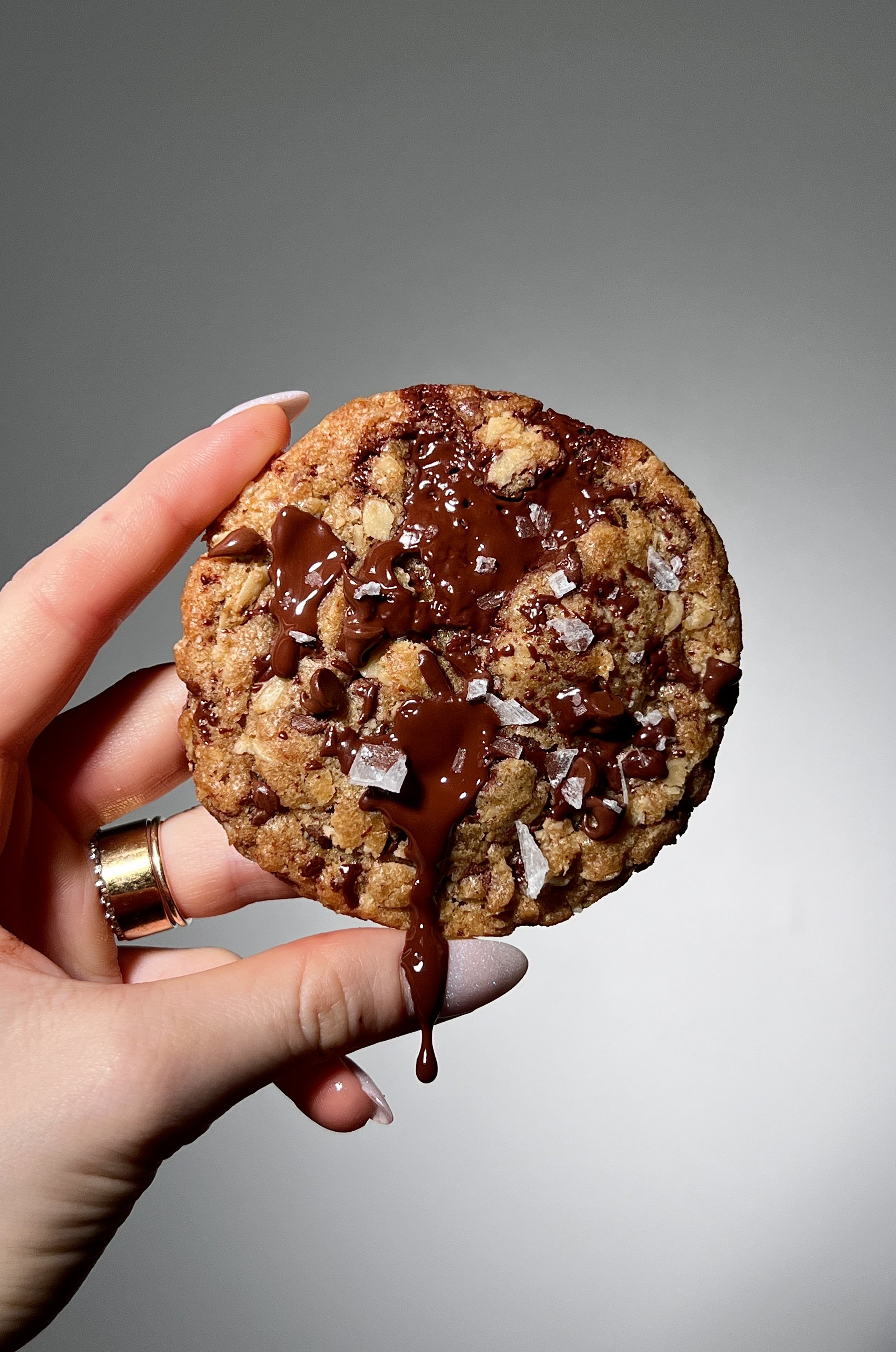 Brown butter oatmeal chocolate chip cookies with crisp golden edges and gooey centers, studded with melty chocolate chips and finished with flaky sea salt, served warm with a glass of milk.