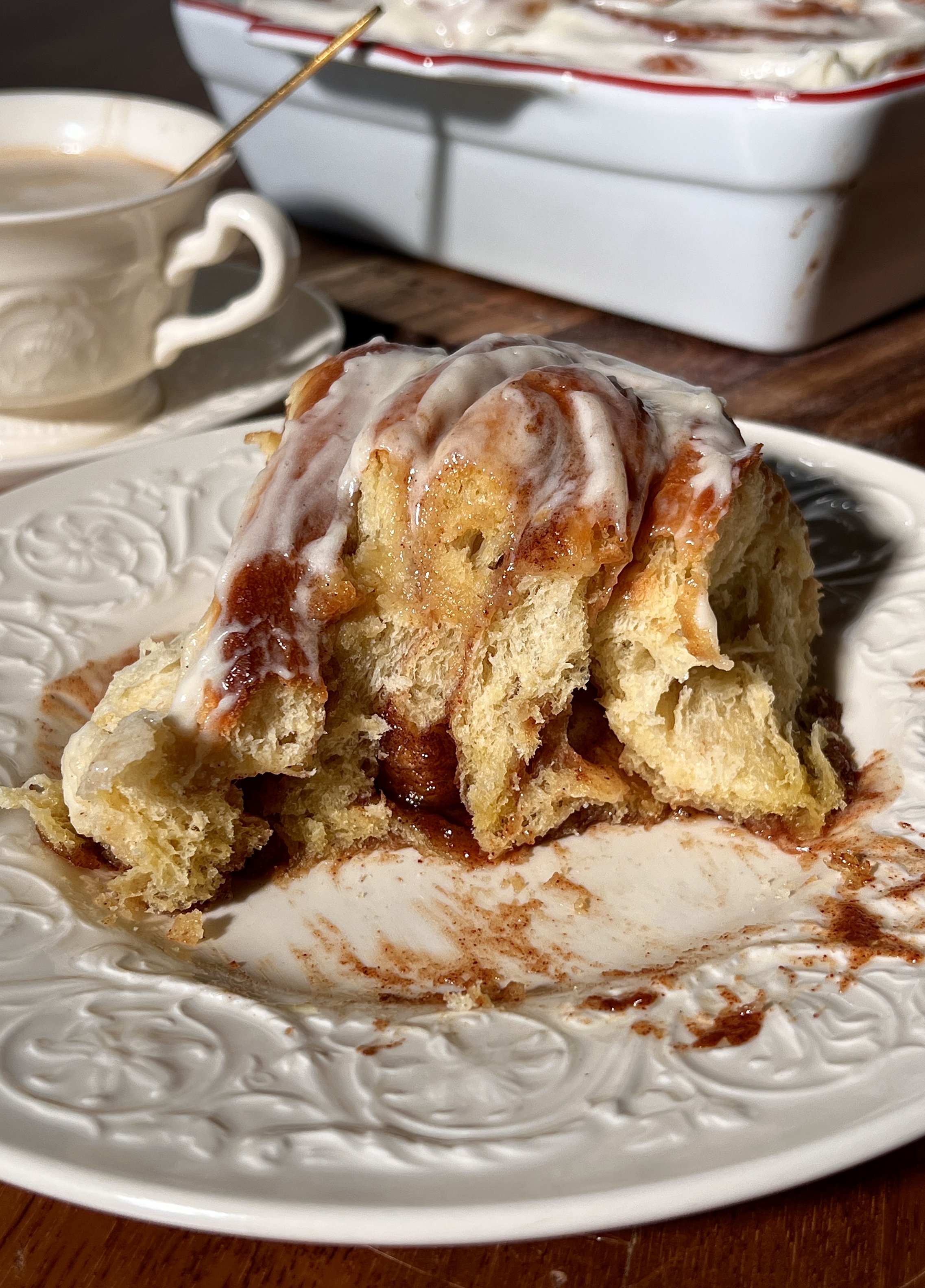 Soft, gooey eggnog cinnamon rolls in a baking dish, swirled with a golden brown sugar cinnamon filling and topped with melting eggnog cream cheese frosting.