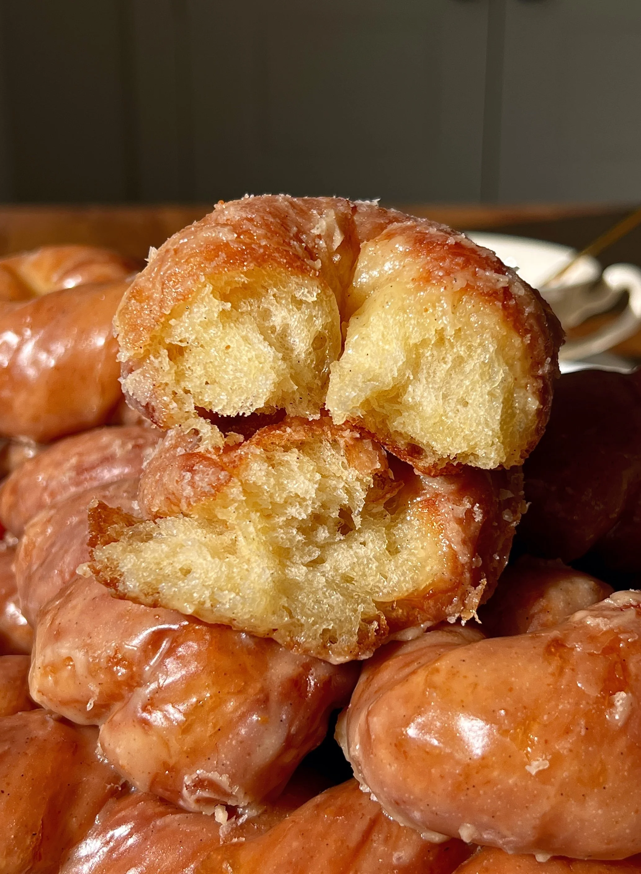 Close-up of a brown butter maple twist donut showing the perfectly golden exterior with a slight chew and pillowy soft milk bread interior glazed in a rich brown butter maple glaze.