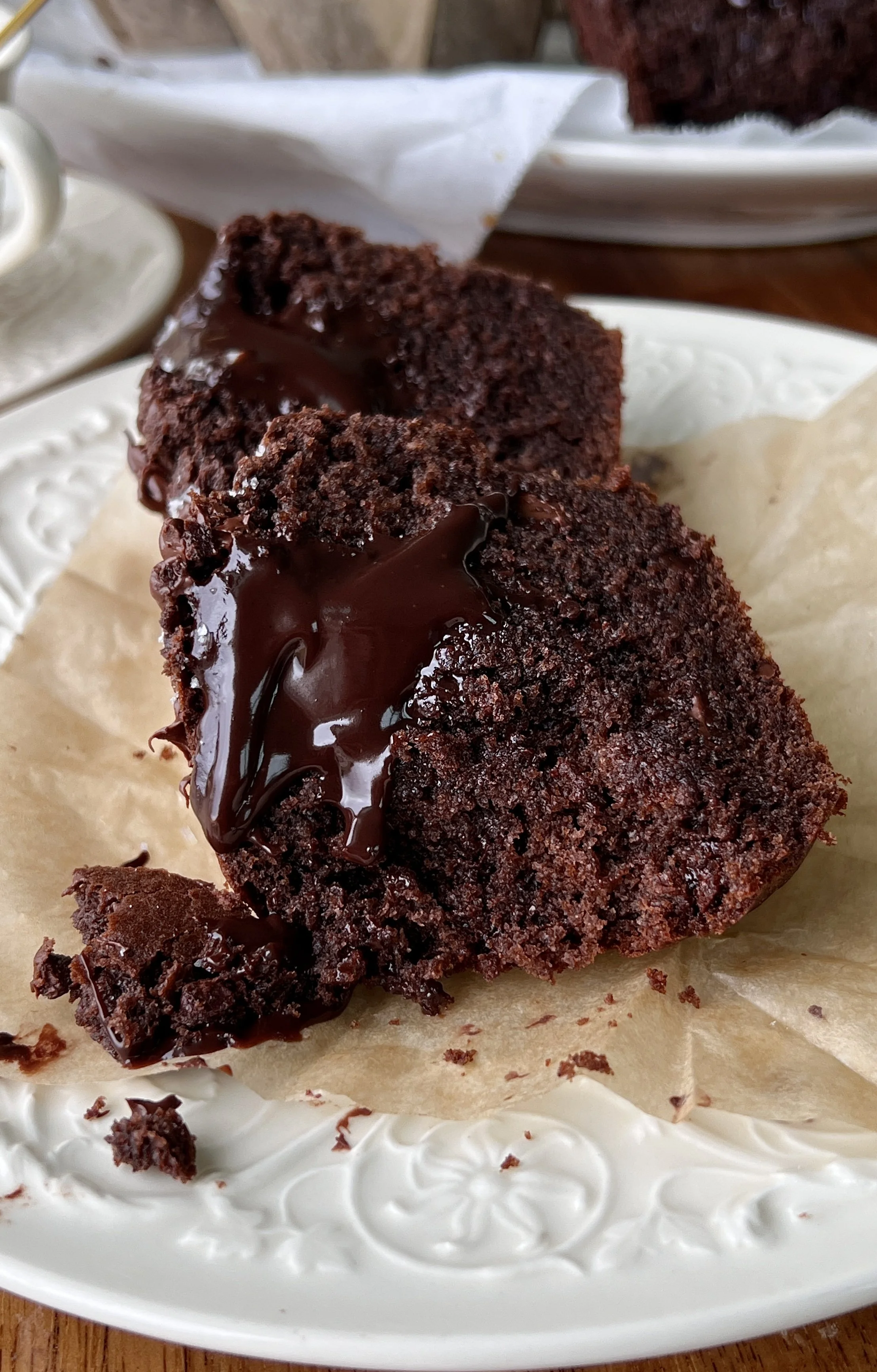 Bakery-style triple chocolate fudge muffin with a bite taken out showing the soft fluffy crumb, melty chocolate chips, and molten chocolate ganache center throughout.