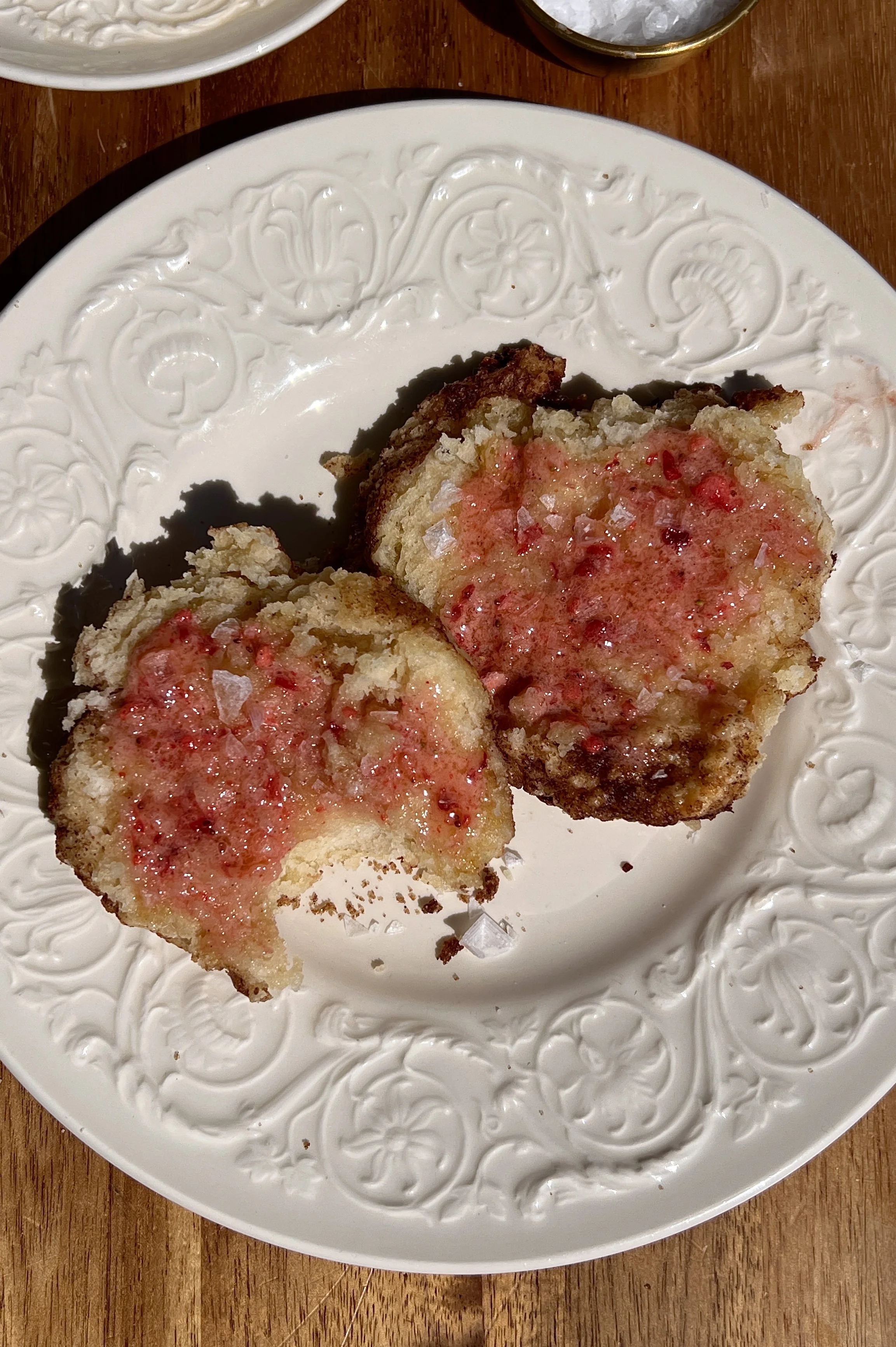 Soft and fluffy cinnamon crunch sourdough cathead biscuits served warm with a generous spread of whipped strawberry honey butter, a sprinkle of flaky sea salt, and a hot cup of coffee.