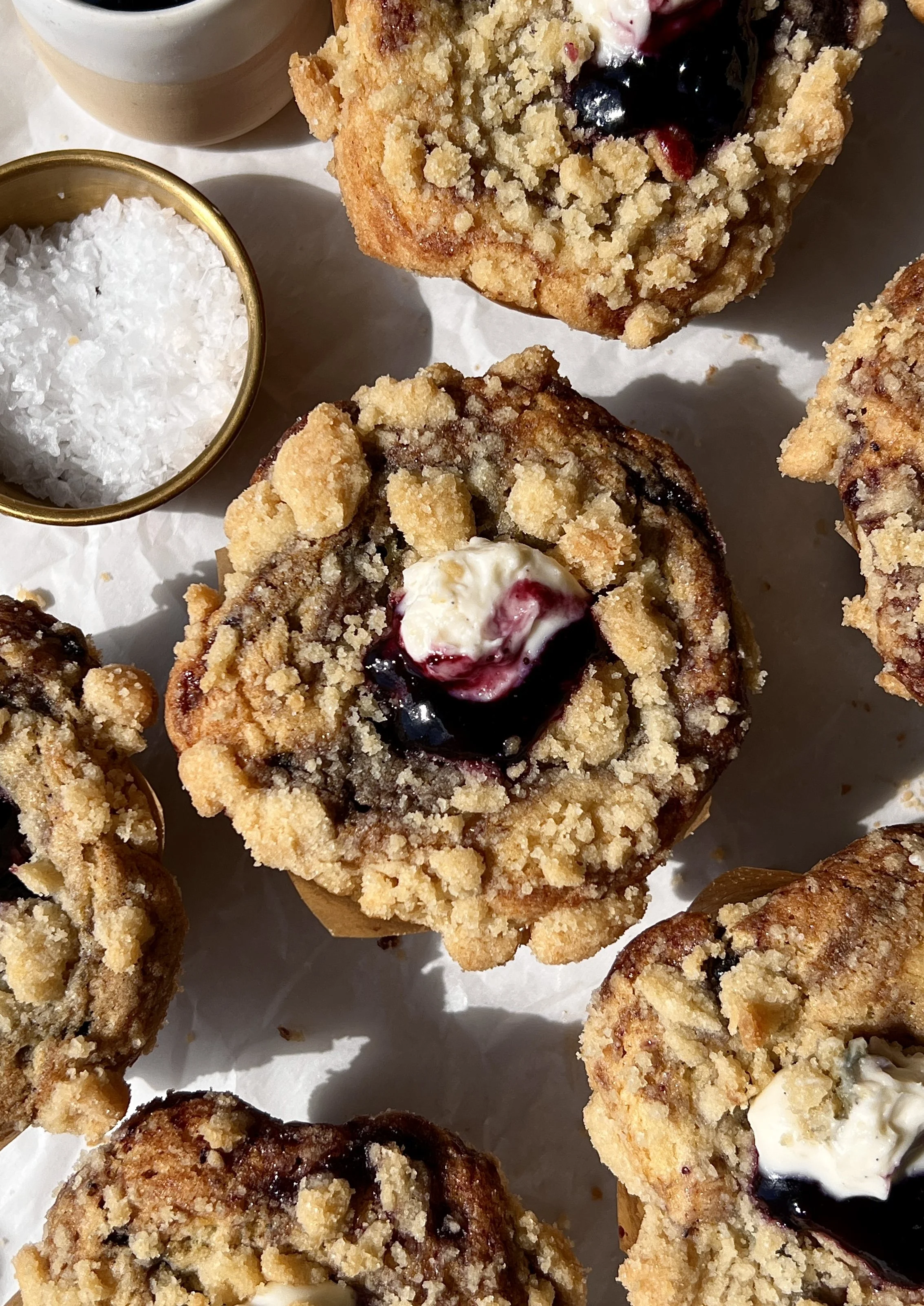 Close-up of a soft and buttery blueberry muffin cheesecake cookie cup with a rich and creamy cheesecake filling and perfectly golden crumble topping throughout.