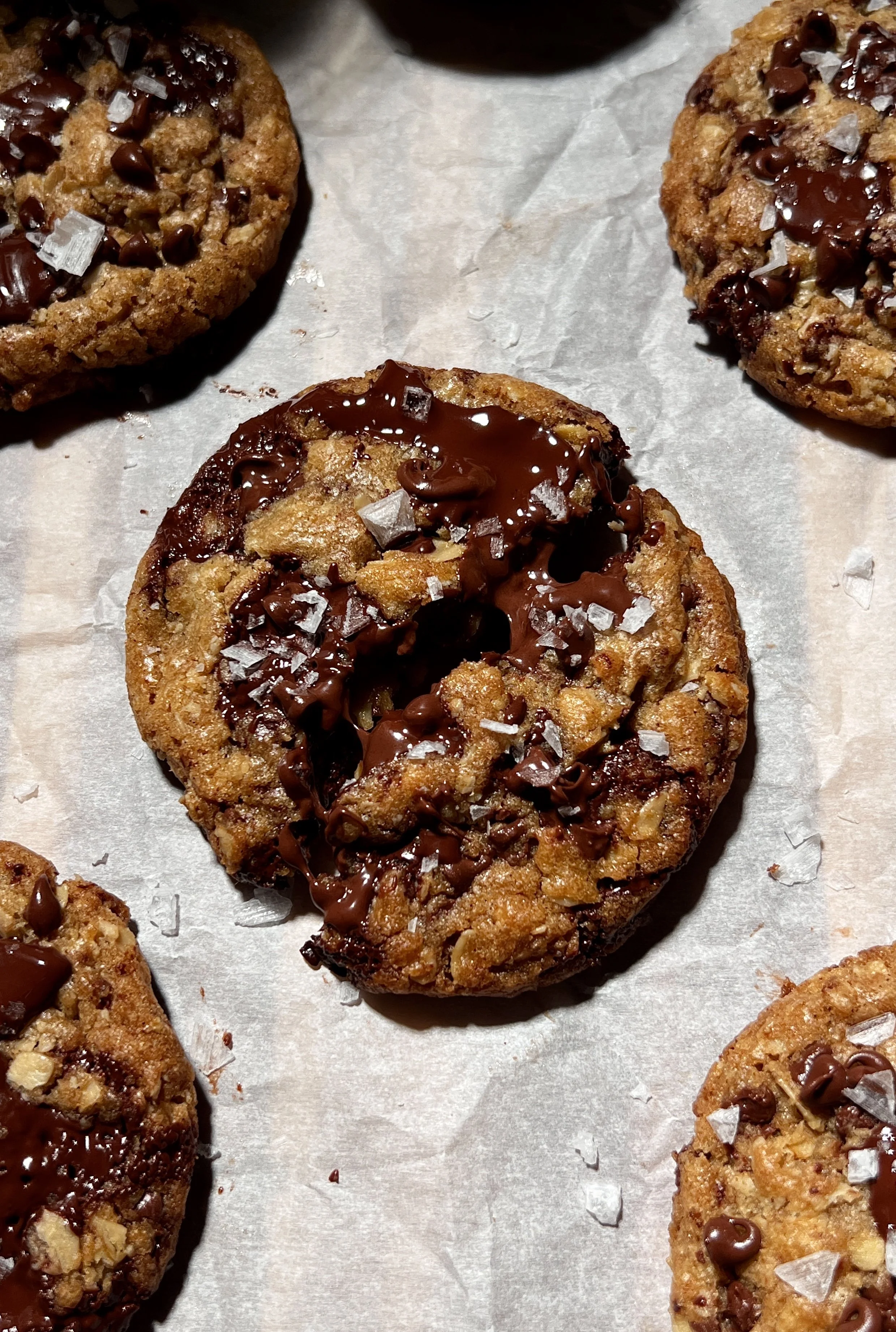 Brown butter oatmeal chocolate chip cookies with crisp golden edges and gooey centers, studded with melty chocolate chips and finished with flaky sea salt, served warm with a glass of milk.