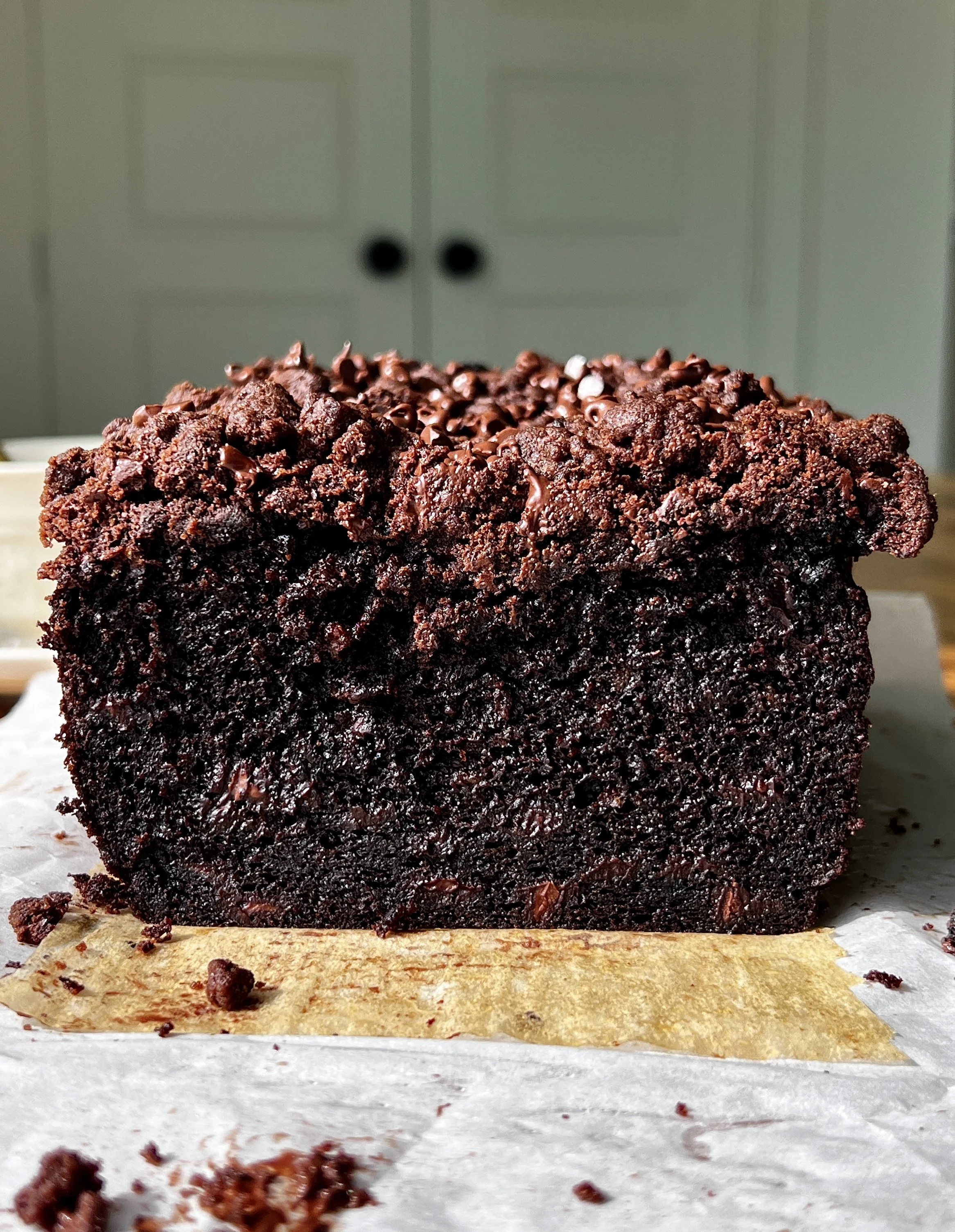 Slice of double chocolate crumb banana bread with brown butter showing the soft fluffy crumb, melty chocolate chips, and chocolate chip chocolate crumb topping served warm with a pat of butter and flaky sea salt.