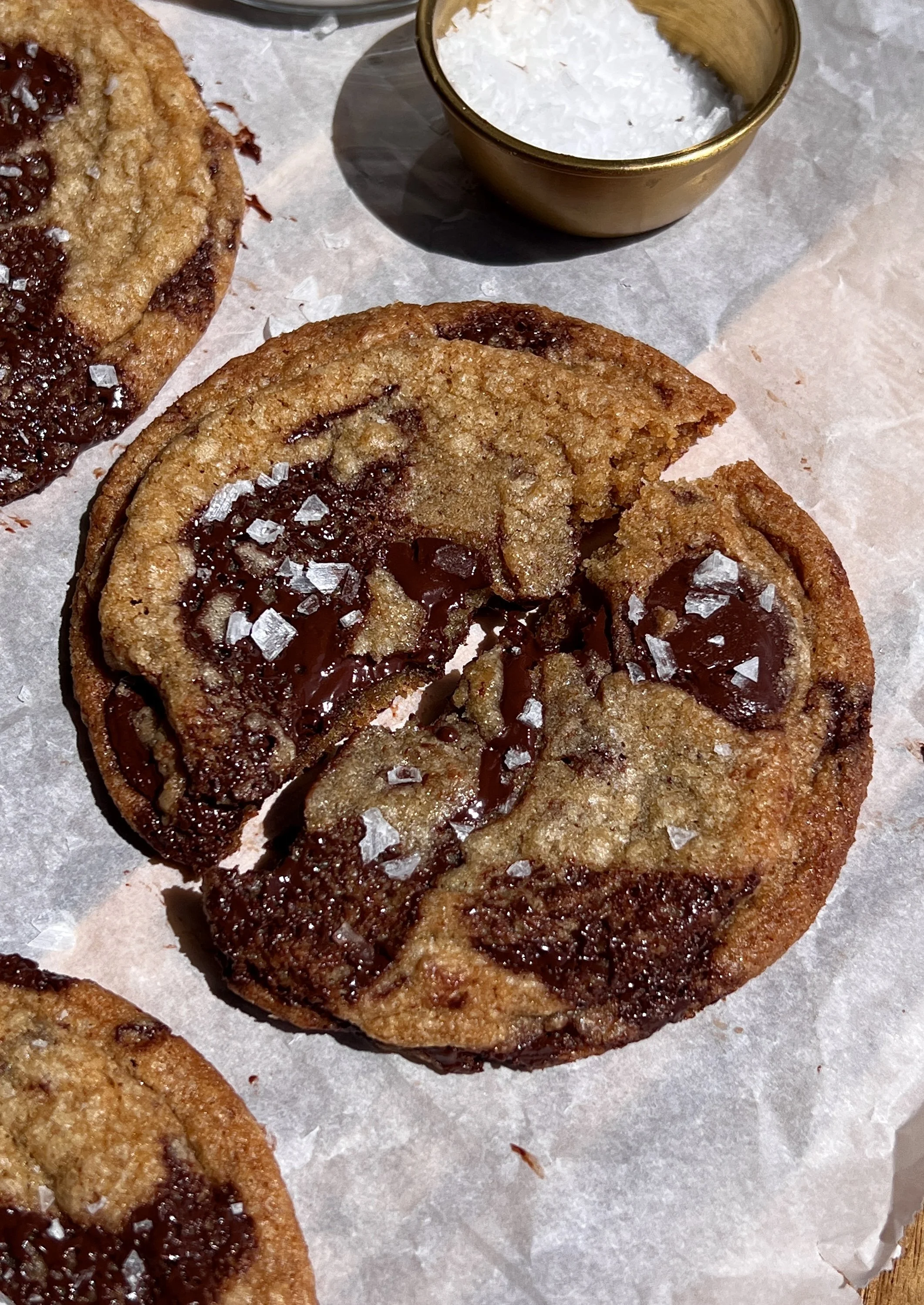 Broken open brown butter chocolate chip cookie showing soft, gooey center and melty chocolate.