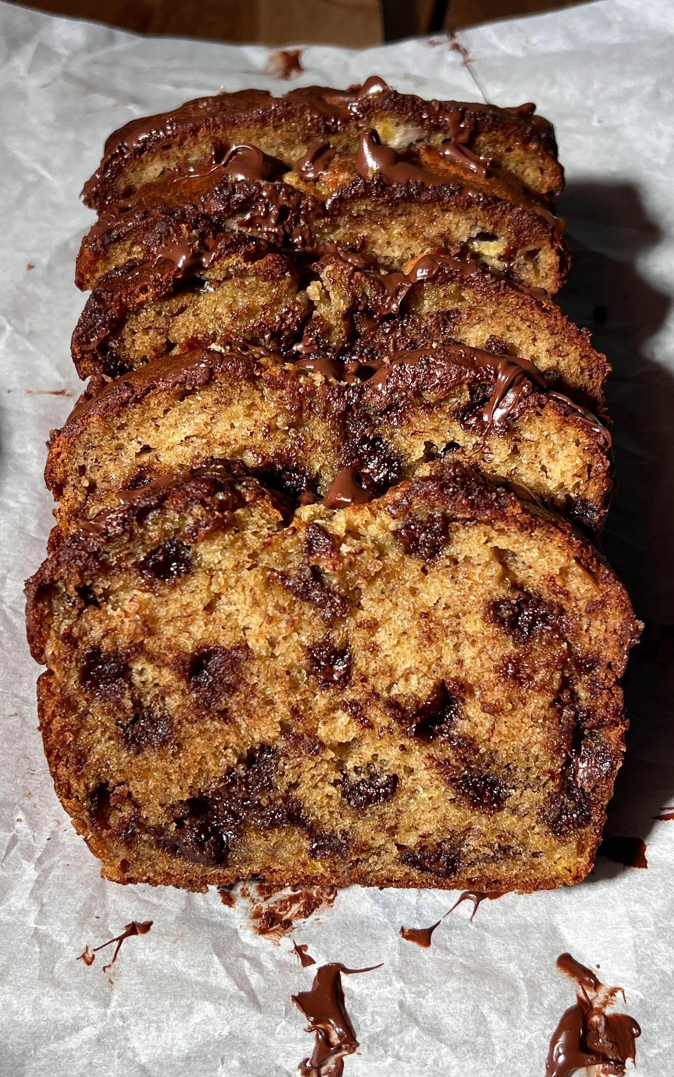 Brown butter banana bread loaf with melty chocolate chips, baked until golden, sliced and served warm with butter, flaky sea salt, and a cup of coffee.