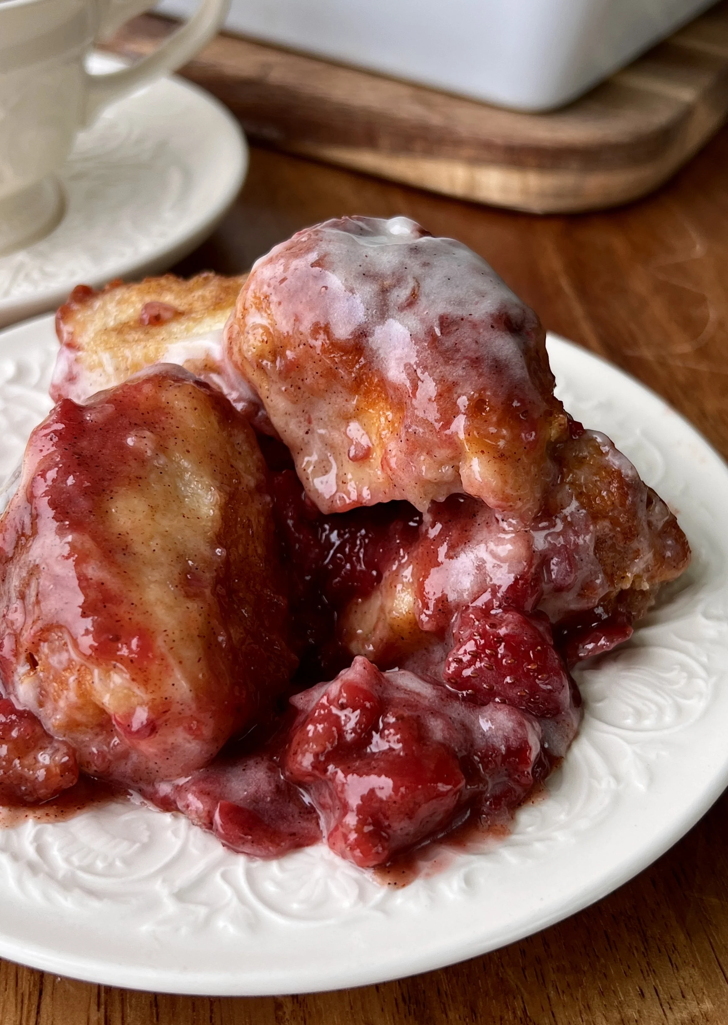 Gooey strawberry cinnamon roll bites being pulled apart showing the soft fluffy interior with bright homemade strawberry compote and brown sugar syrup soaked into every nook.