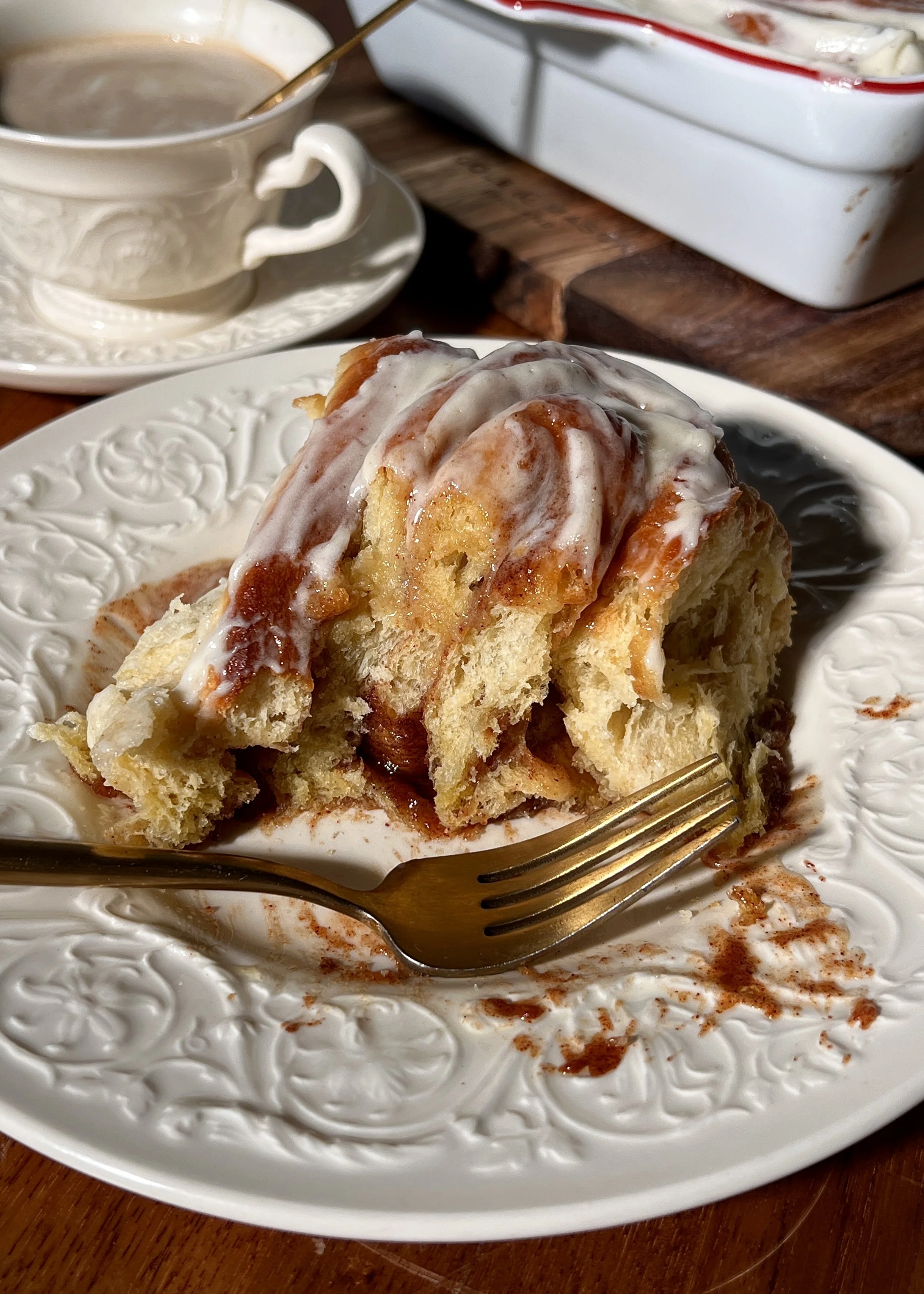 Soft, gooey eggnog cinnamon rolls in a baking dish, swirled with a golden brown sugar cinnamon filling and topped with melting eggnog cream cheese frosting.