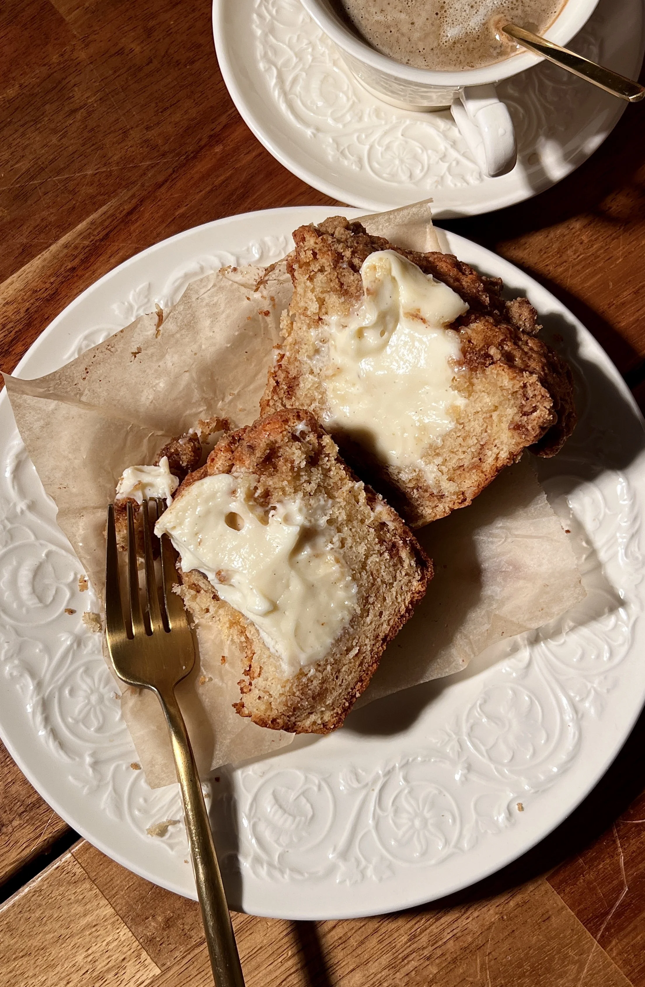 Brown butter cinnamon roll cream cheese muffins with a tender crumb, cinnamon swirl throughout, and a crumb topping, served warm with a cup of coffee.