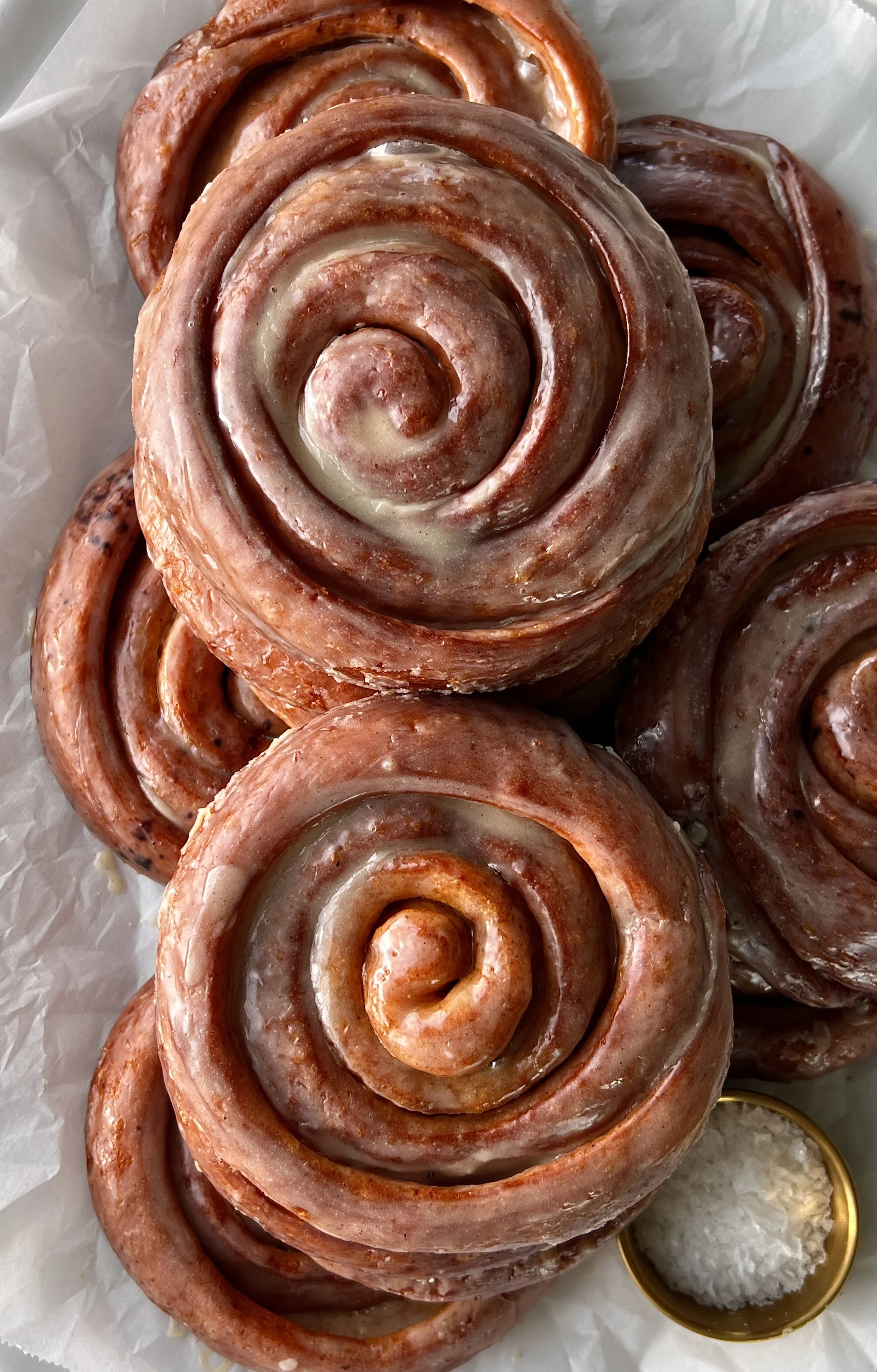 Close-up of a pumpkin spice honey bun showing the soft pillowy pumpkin dough with gooey swirls of honey butter and pumpkin spice brown sugar filling and a honey glaze sinking into every crack.