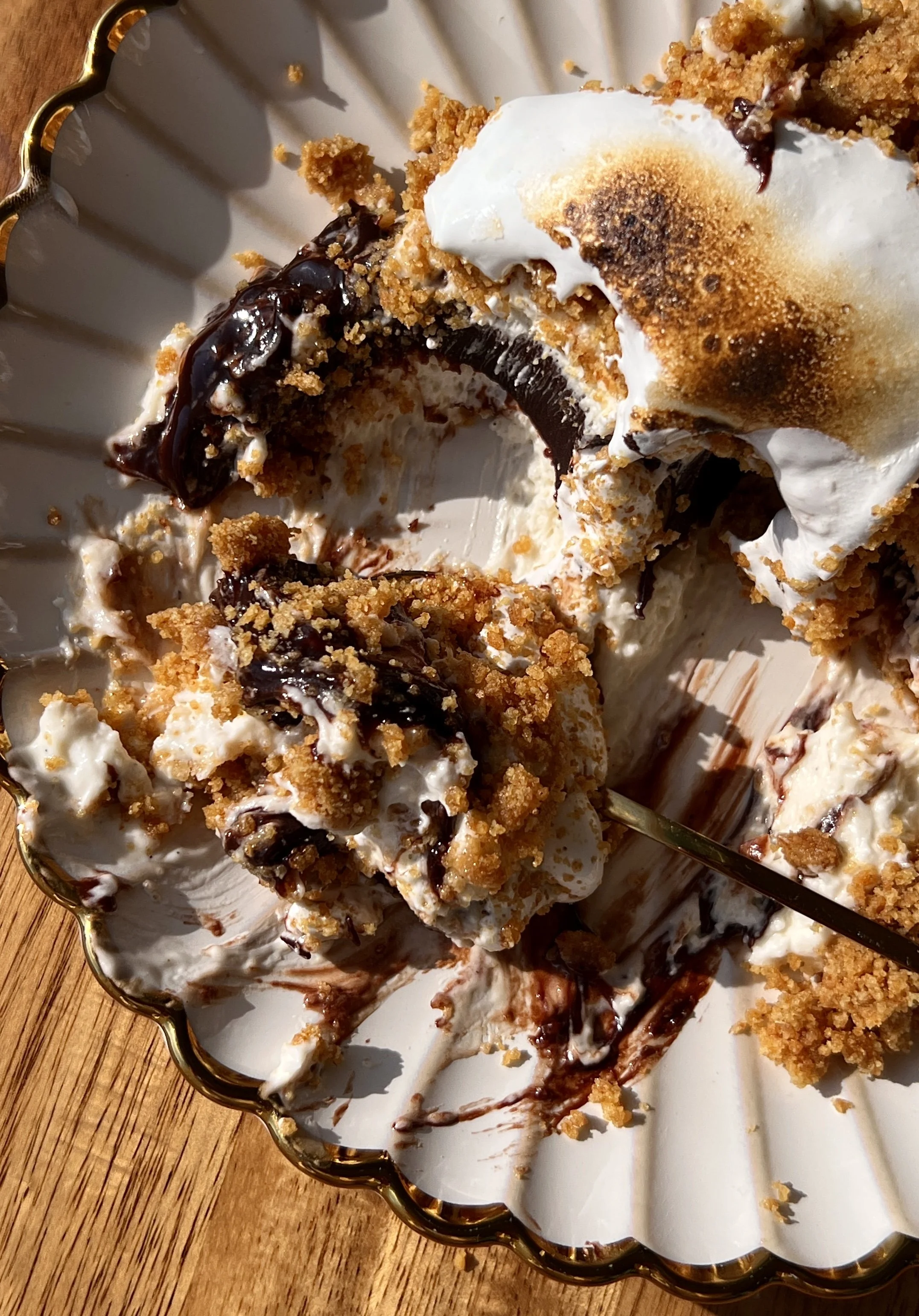 Upside down s'mores no-bake cheesecake with a perfectly crunchy graham cracker crust inverted to serve and finished with a dollop of toasted marshmallow fluff on top.