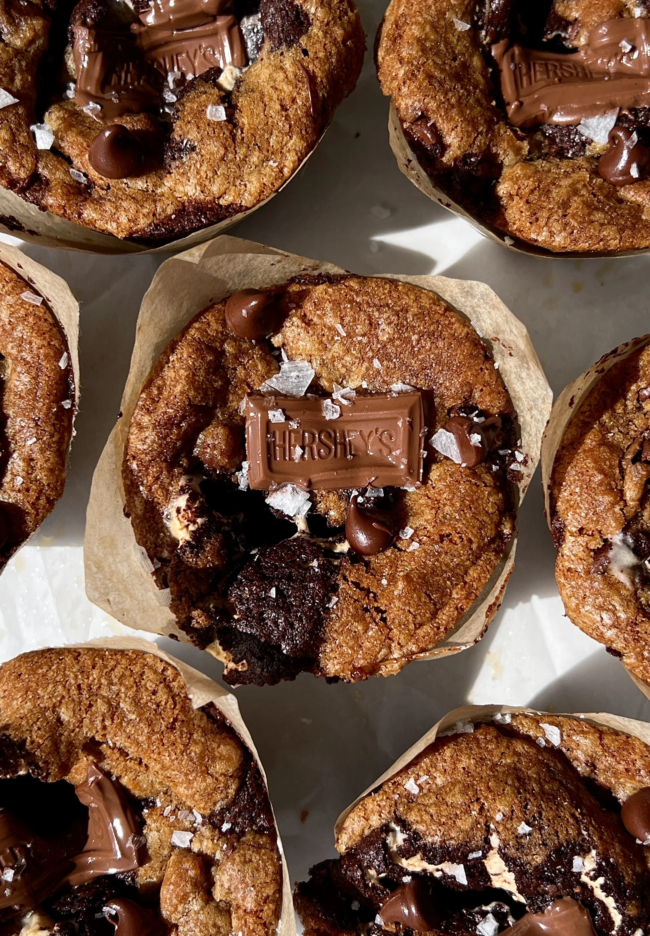 Close-up of a fudgy brown butter s'mores brookie cup with a golden crisp exterior showing the layers of brown butter cookie dough, brownie, graham cracker, marshmallow, and melty milk chocolate throughout.