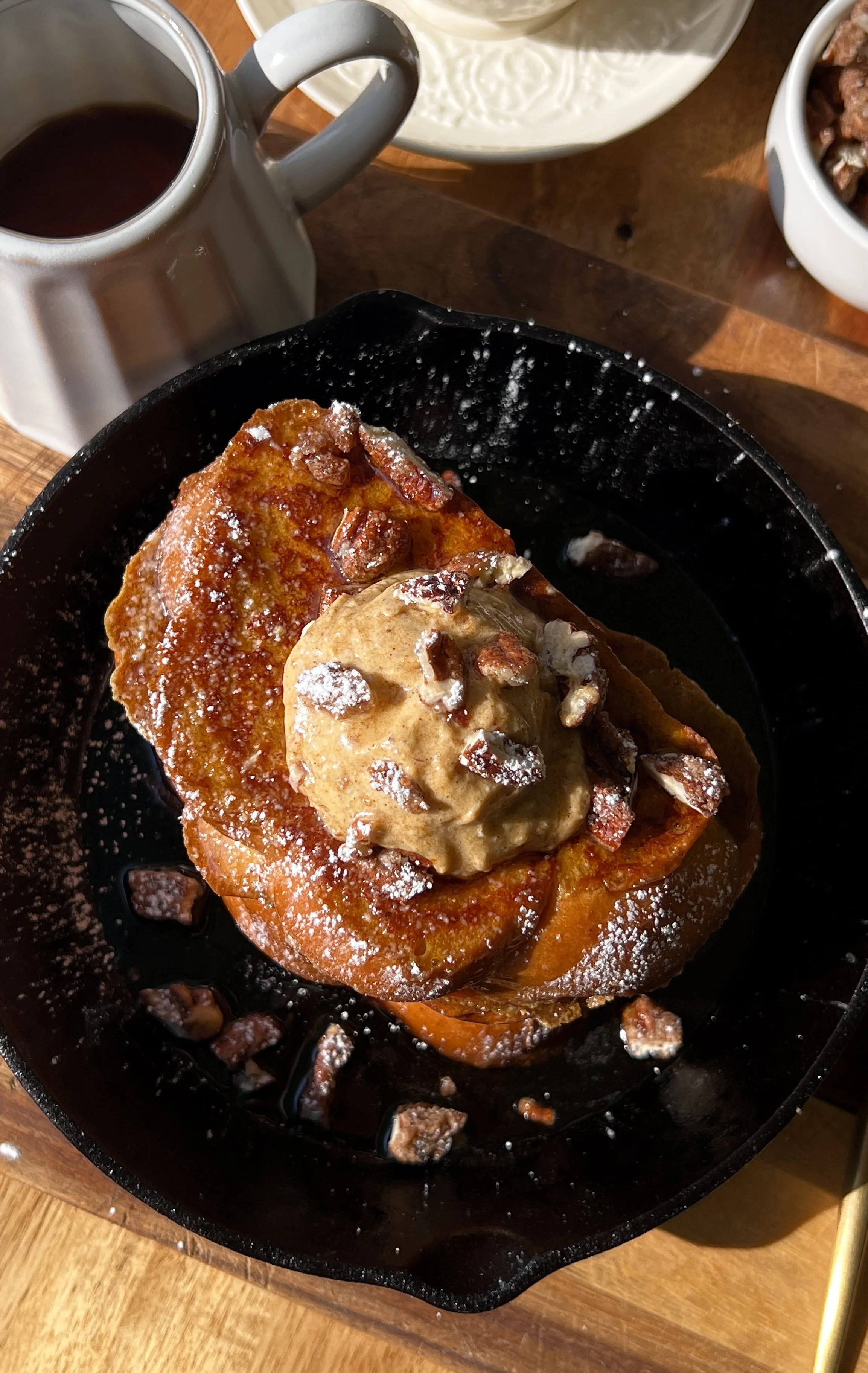 Stack of golden pumpkin spice french toast slices served warm with a pat of butter, whipped pumpkin mascarpone, a dusting of powdered sugar, and a drizzle of maple syrup.