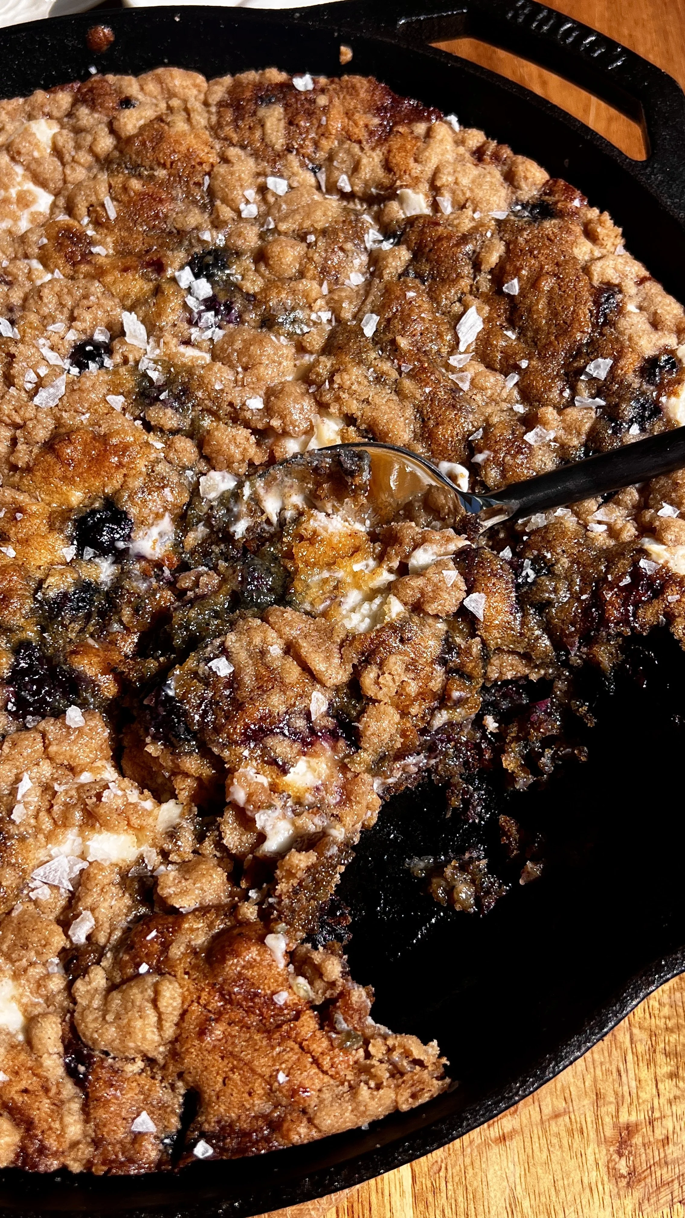 Close-up of brown butter blueberry cookie skillet with gooey center, cheesecake filling, and blueberry jam swirls.