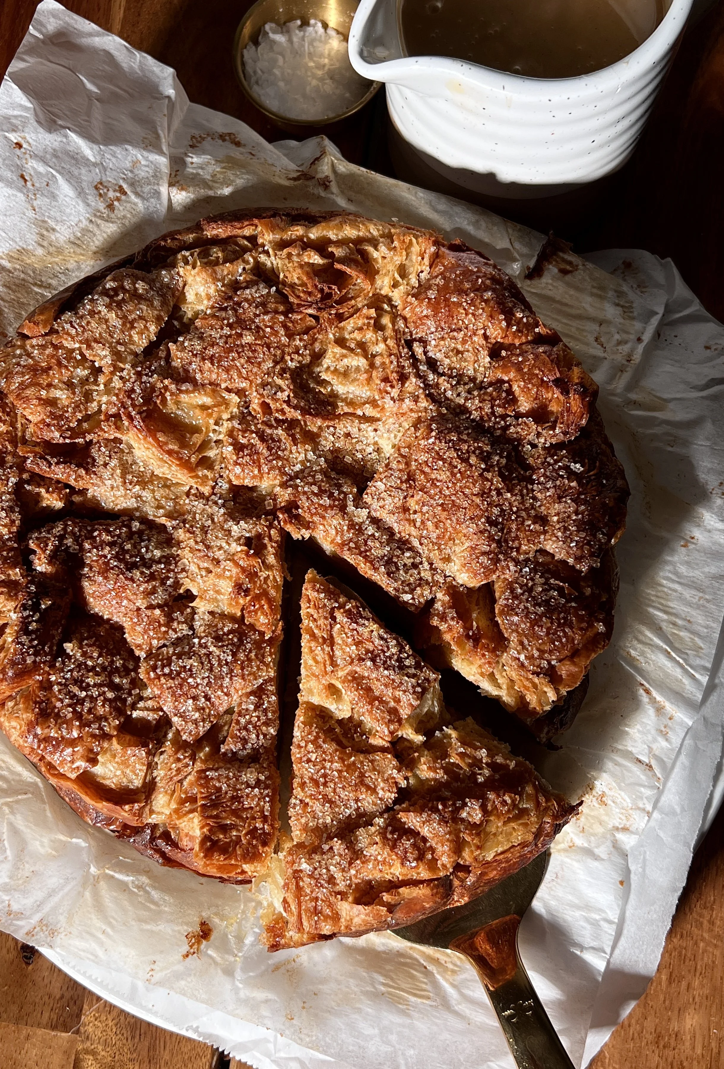 Warm vanilla bean croissant bread pudding with a golden crisp top, served with buttered caramel rum sauce and a scoop of vanilla ice cream.