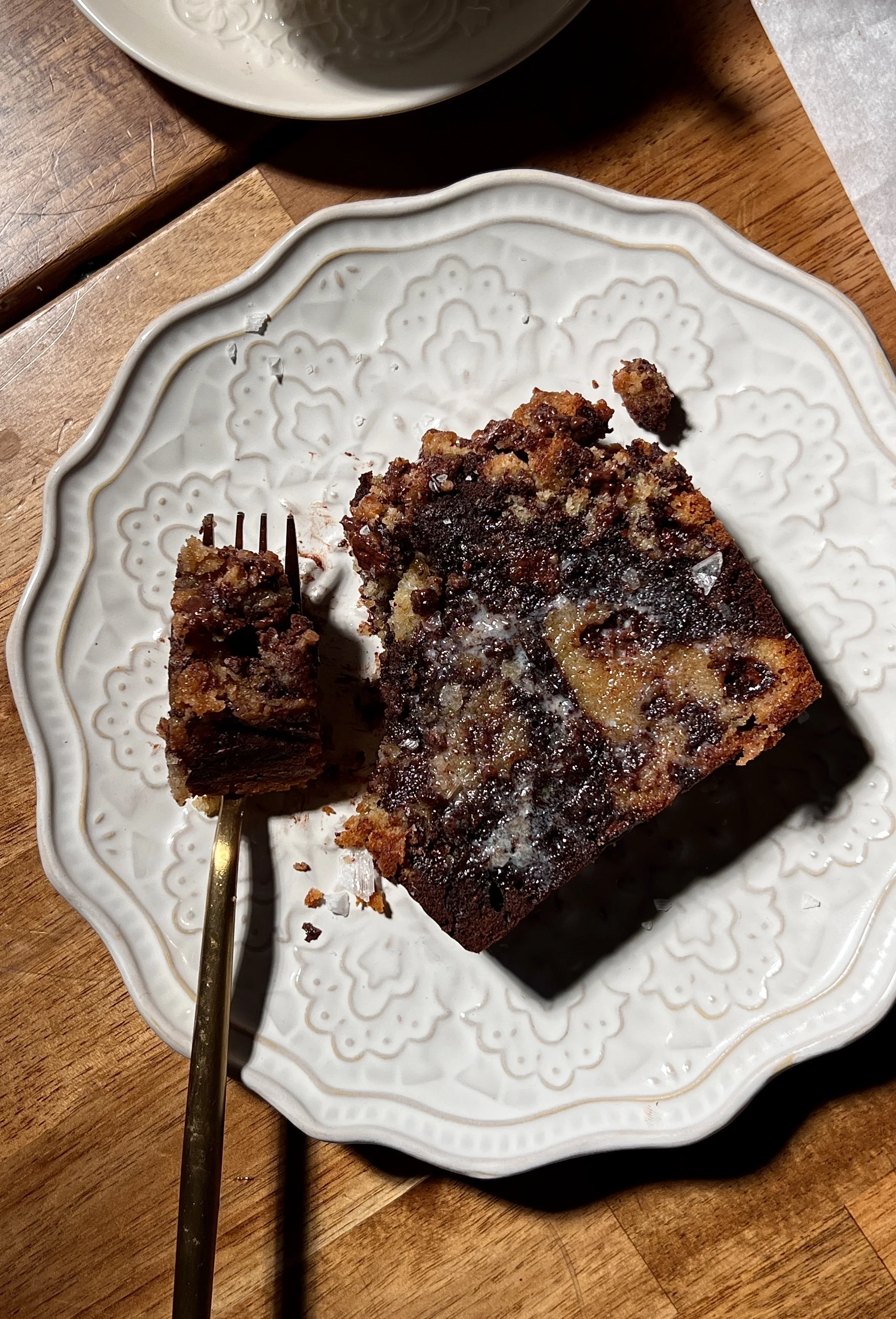 Brown butter marbled chocolate chip crumb loaf cake sliced and served warm, showing vanilla and chocolate swirled crumb, melty chocolate chips, and a buttery crumb topping, finished with flaky sea salt and coffee on the side.