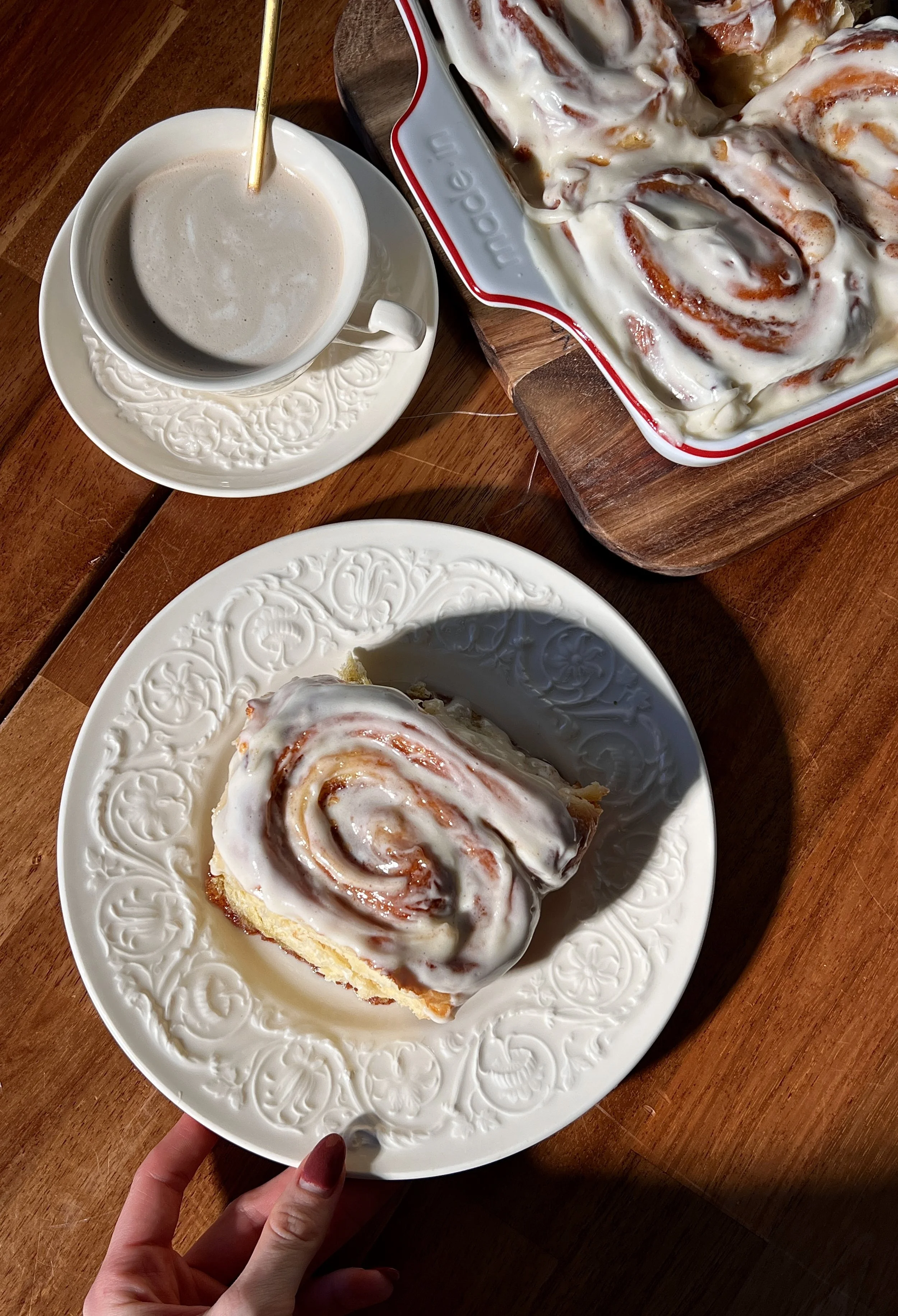Soft, gooey eggnog cinnamon rolls in a baking dish, swirled with a golden brown sugar cinnamon filling and topped with melting eggnog cream cheese frosting.