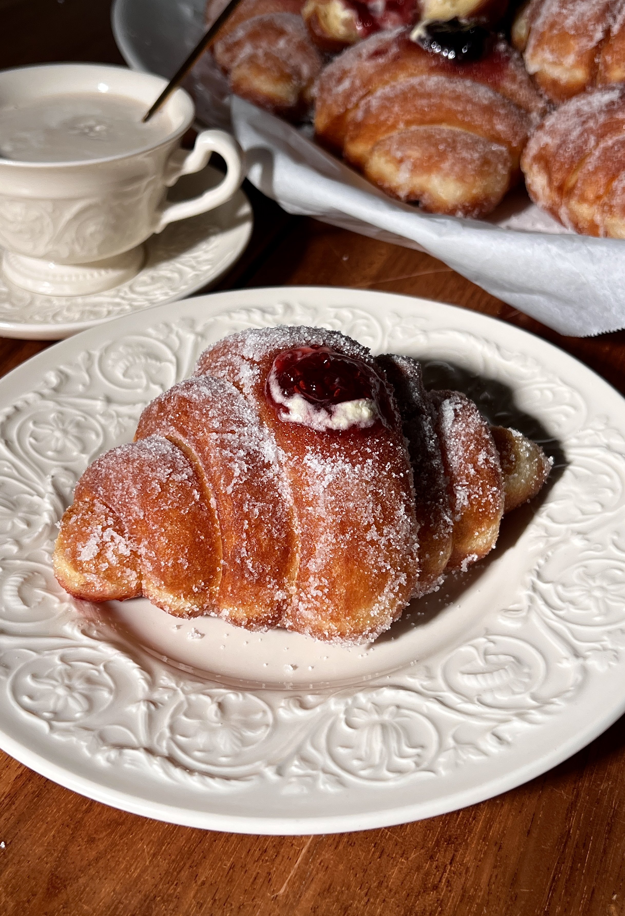 Croissant-shaped doughnuts filled with vanilla bean custard and raspberry jam, rolled in sugar and fried until golden.