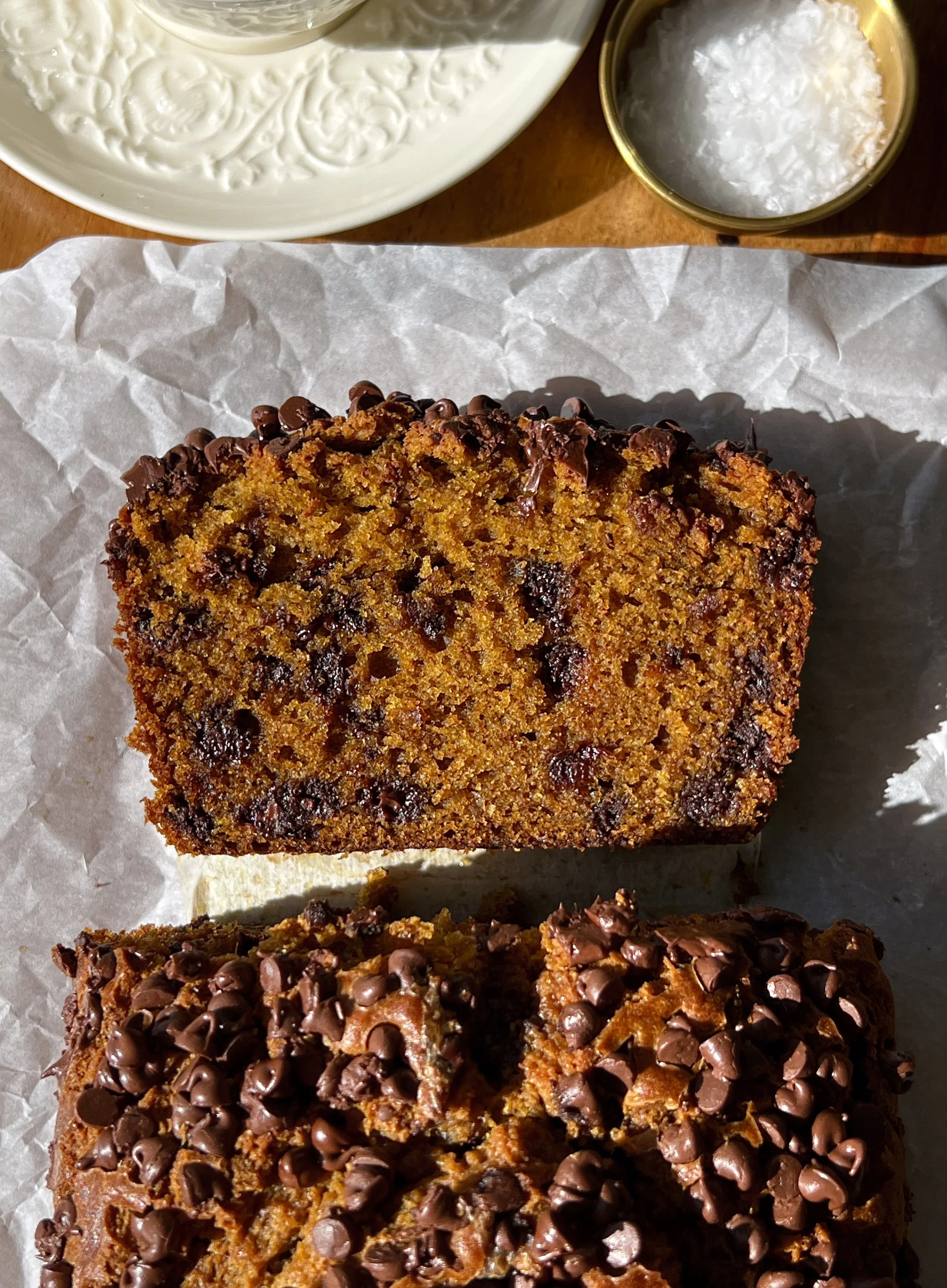 Slice of brown butter chocolate chip pumpkin bread showing the soft and tender spiced pumpkin crumb with melty chocolate chips studded throughout served warm with a pat of butter and a sprinkle of flaky sea salt.