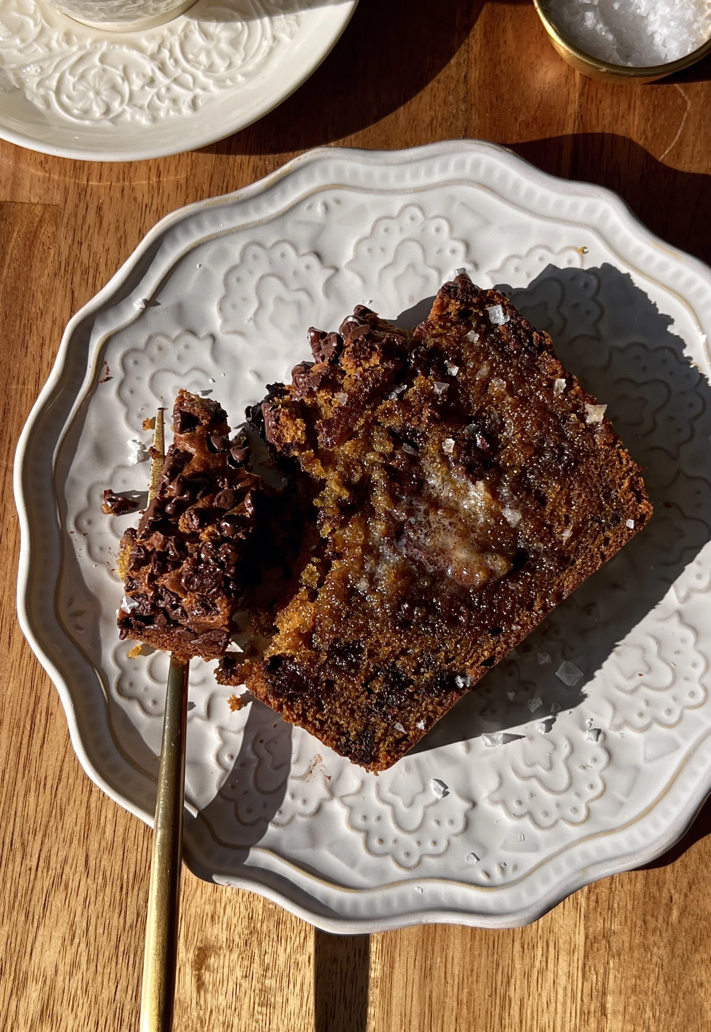 Soft and tender brown butter chocolate chip pumpkin bread with a perfectly golden and slightly crisp exterior and melty chocolate chips throughout served warm with a pat of butter a sprinkle of flaky sea salt and a hot cup of coffee.