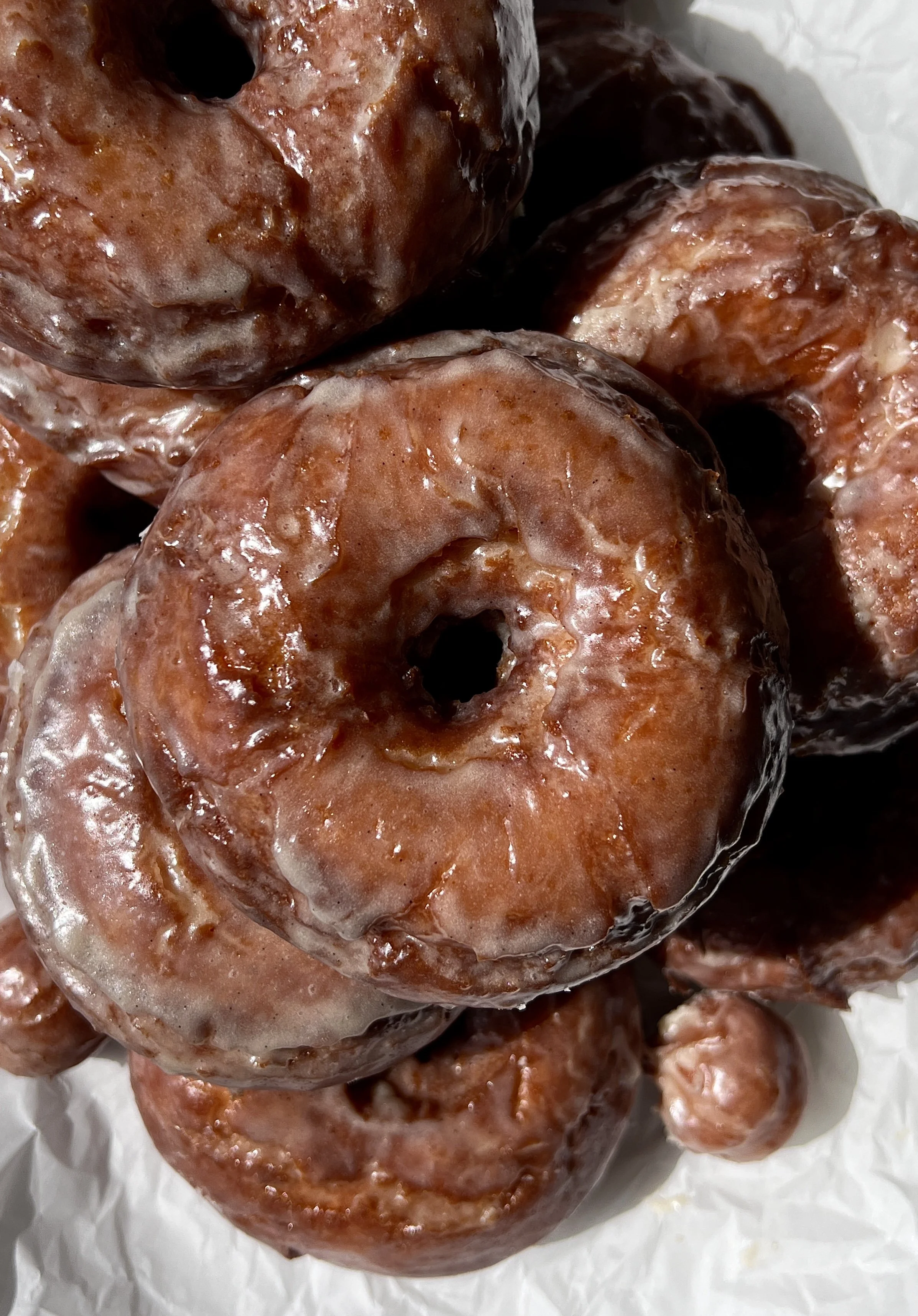 Close-up of a soft and fluffy old-fashioned sour cream donut with a beautifully golden and slightly crisp exterior coated in a silky vanilla bean glaze.