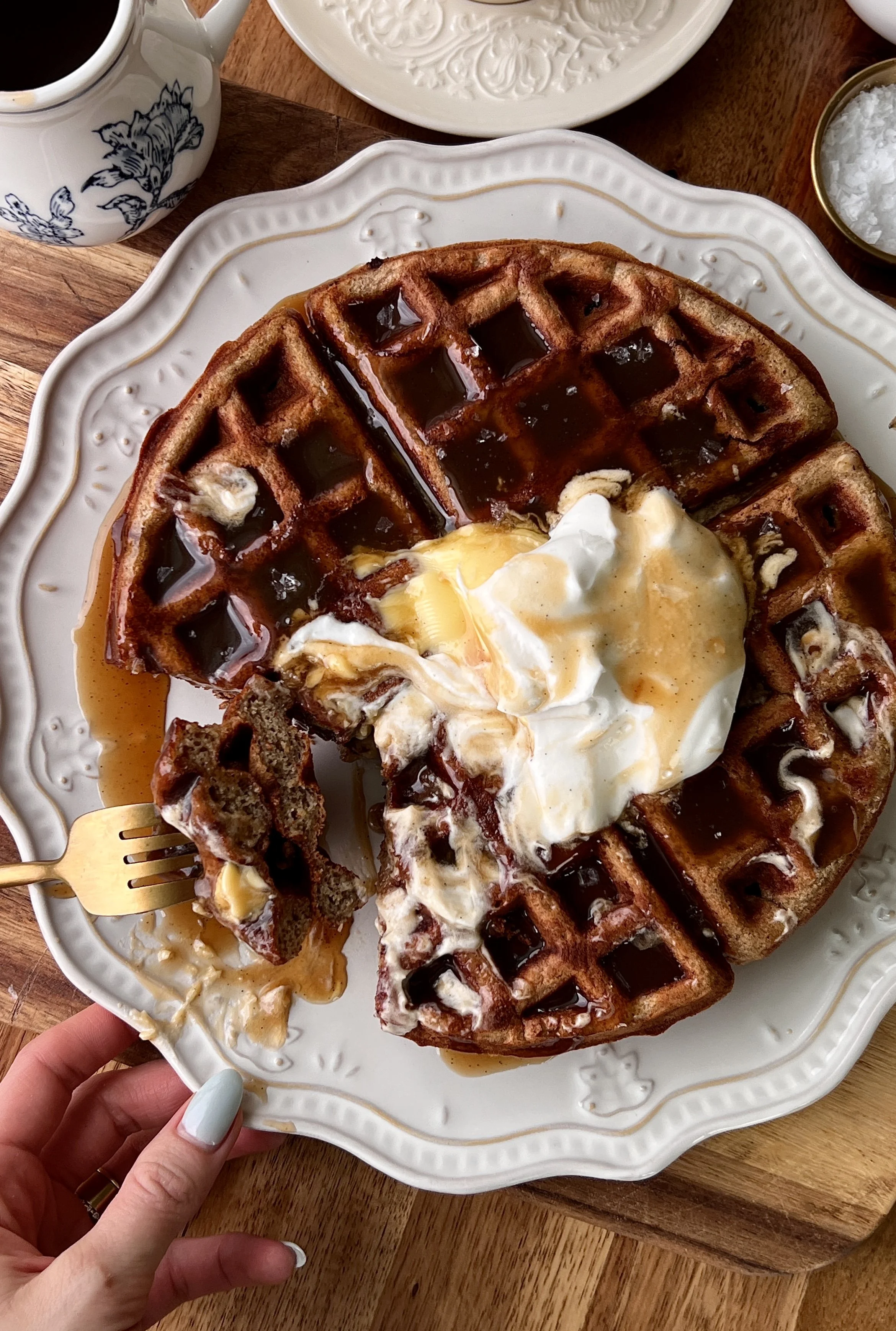 Soft and fluffy sticky toffee waffles with a perfectly golden crisp exterior served warm with butter, a dollop of whipped sour cream topping, and a drizzle of silky maple toffee sauce that melts into every nook served with a hot cup of coffee.