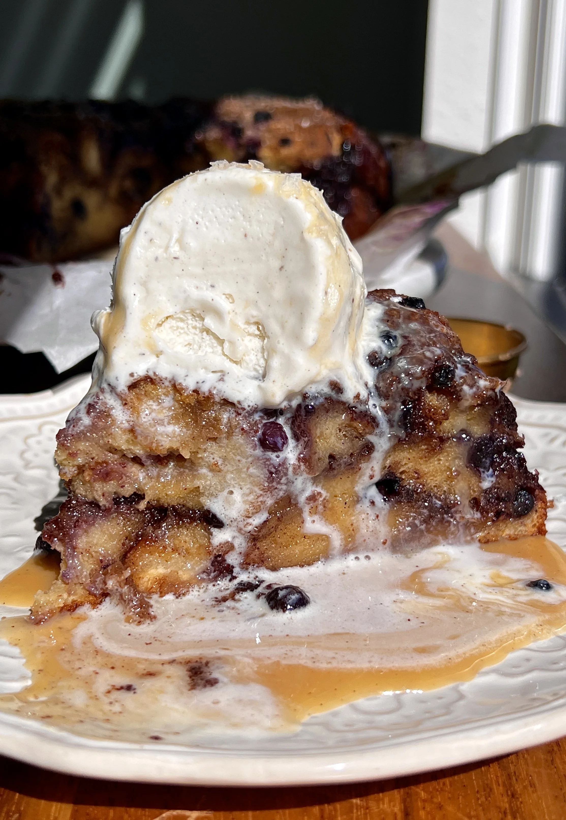 Soft and golden blueberry cinnamon roll bread pudding made with brioche bread and vanilla bean custard served warm with a scoop of vanilla ice cream and flaky sea salt.