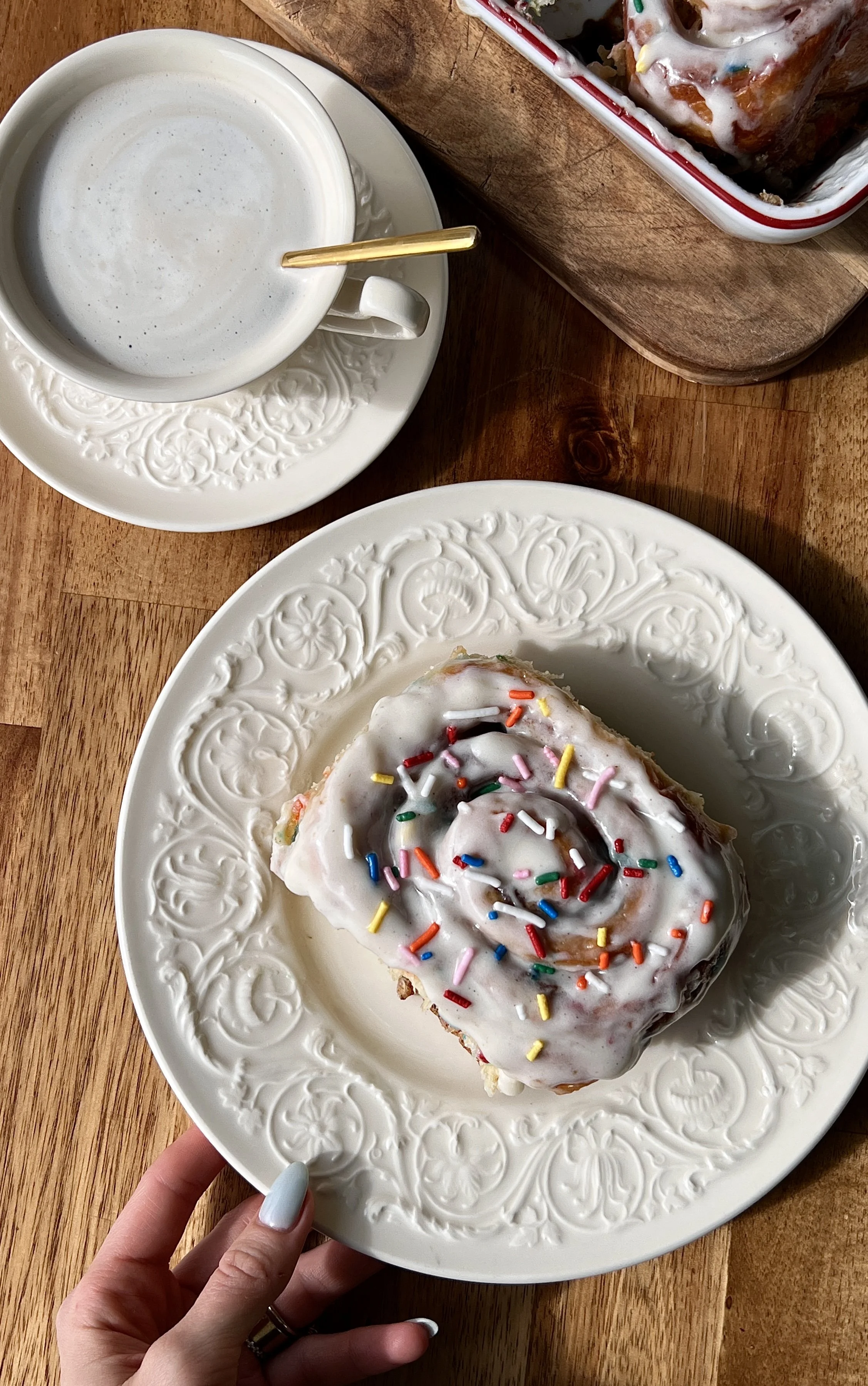 Pillowy soft and fluffy funfetti cinnamon rolls with a gooey brown sugar cinnamon filling finished with smooth cream cheese frosting and rainbow sprinkles served warm with a hot cup of coffee.