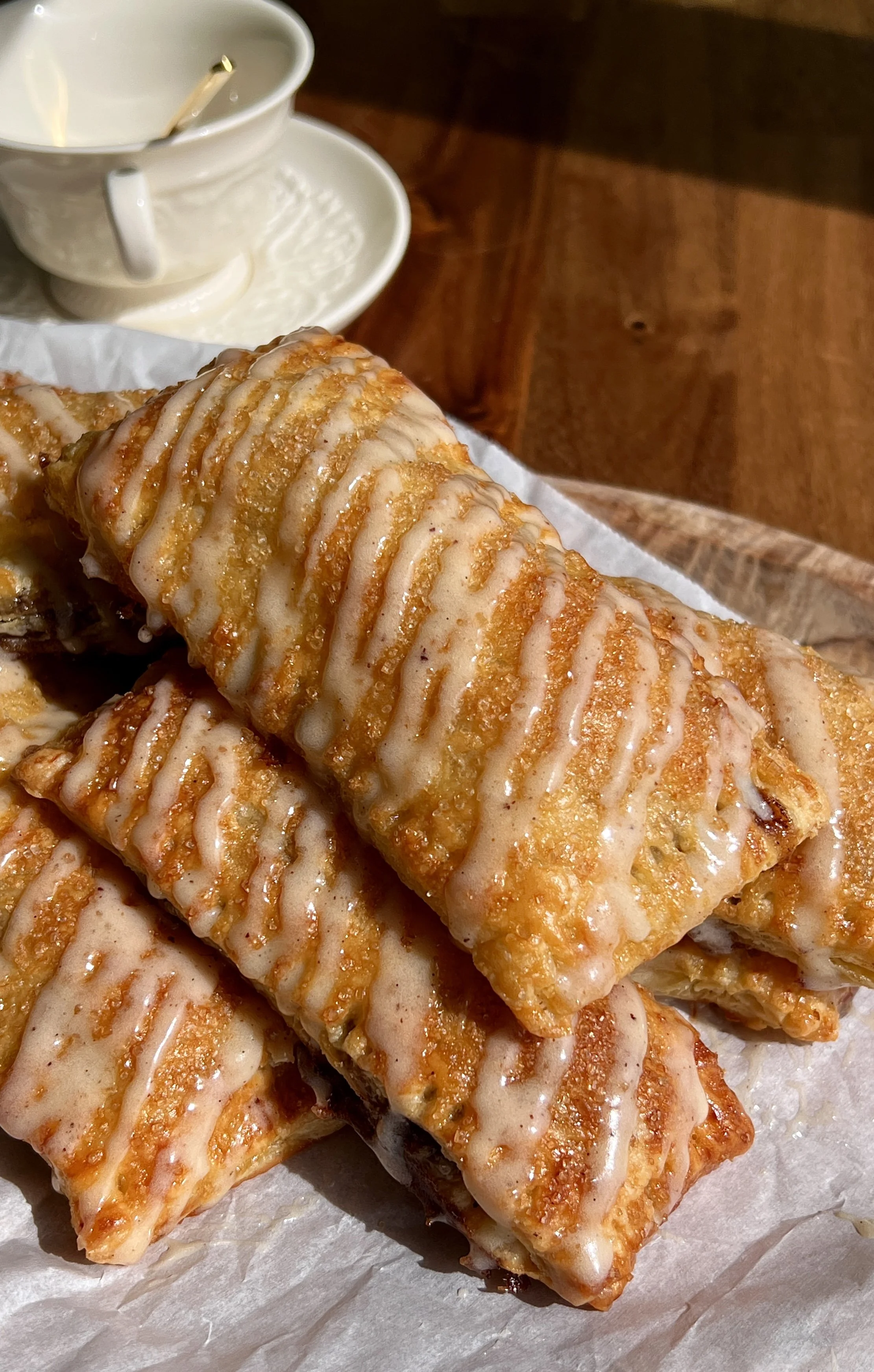 Close-up of a golden cinnamon roll toaster strudel showing flaky puff pastry layers and maple cream cheese glaze.