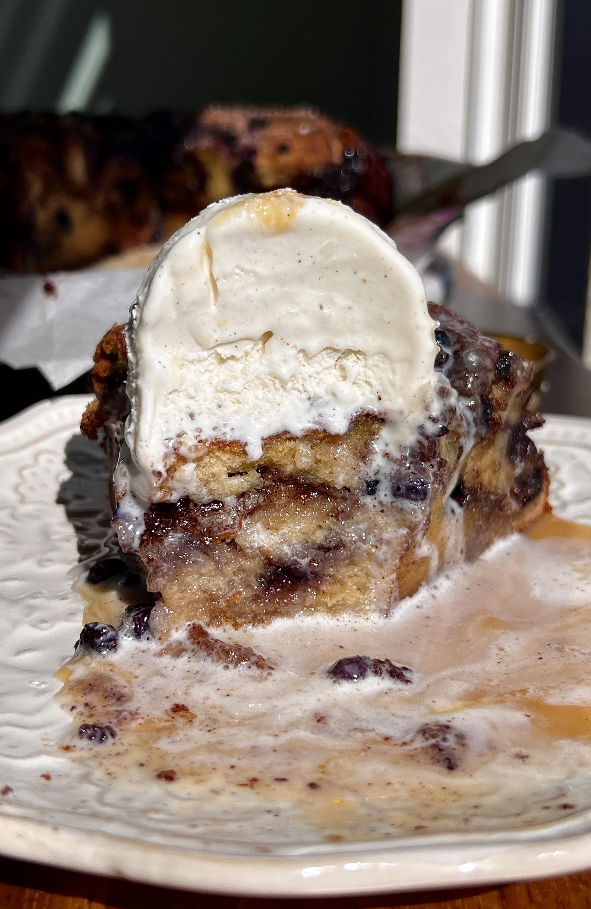 Soft and golden blueberry cinnamon roll bread pudding made with brioche bread and vanilla bean custard served warm with a scoop of vanilla ice cream and flaky sea salt.