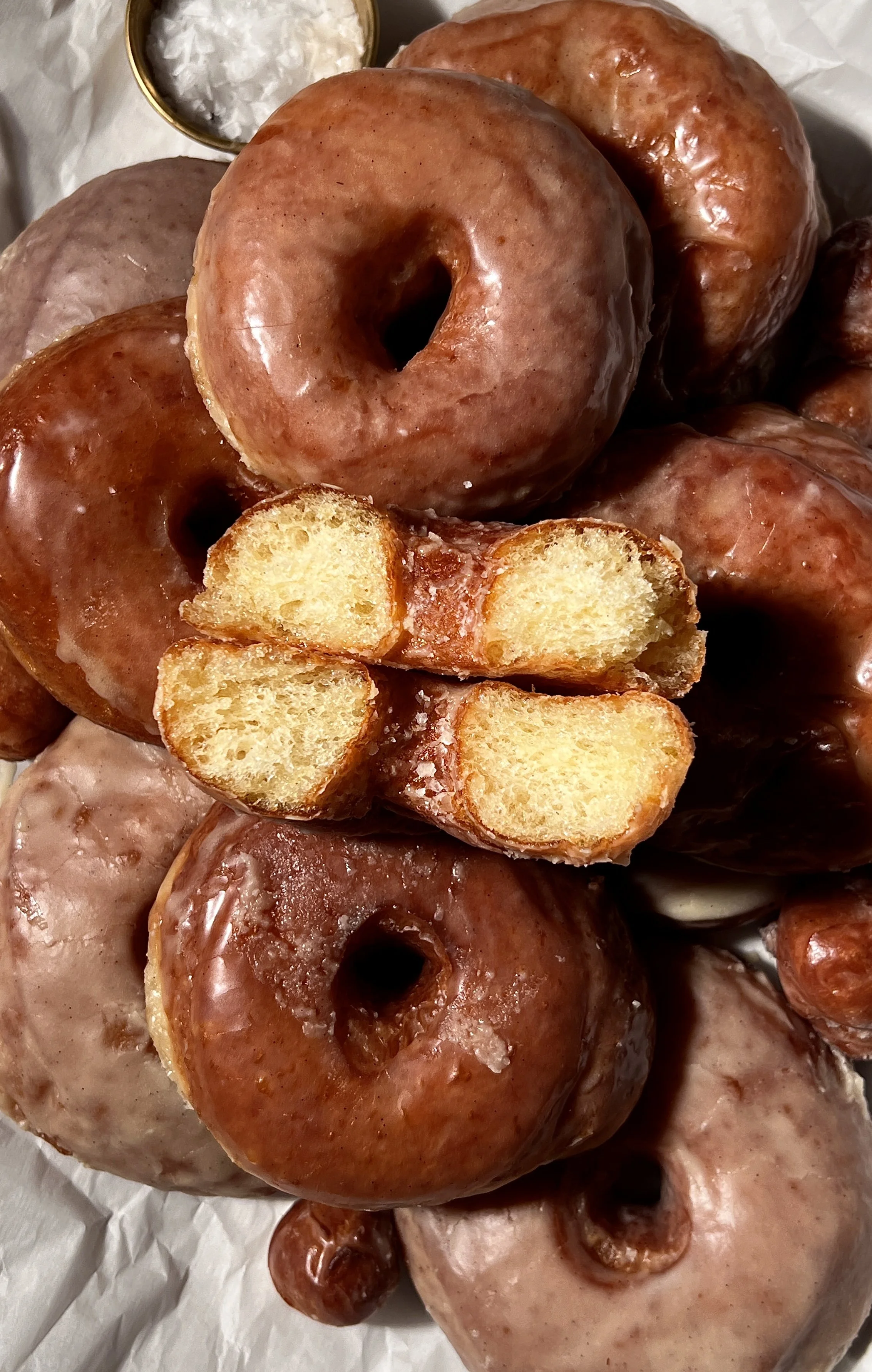 Classic vanilla bean glazed donuts served warm, showing a golden exterior and soft, pillowy interior, coated in a crackly vanilla bean glaze with coffee on the side.