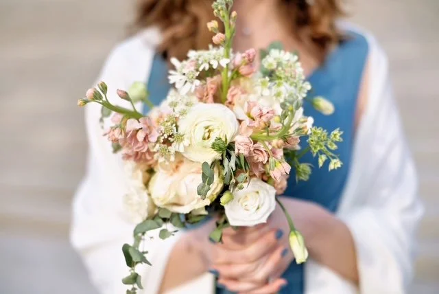 Person holding a bouquet of pink and white flowers with eucalyptus