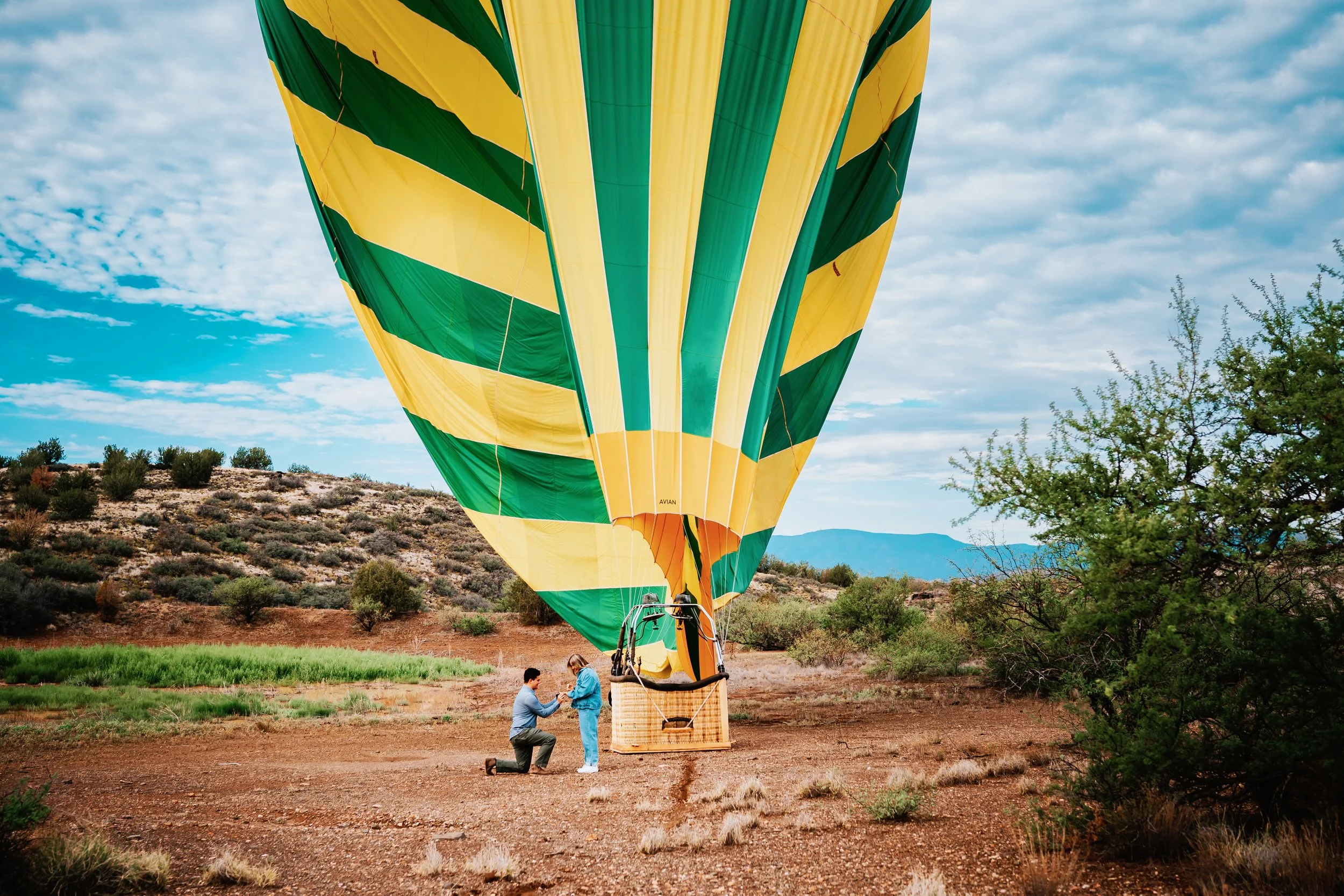 A man proposing to a woman in front of a hot air balloon in Sedona Arizona