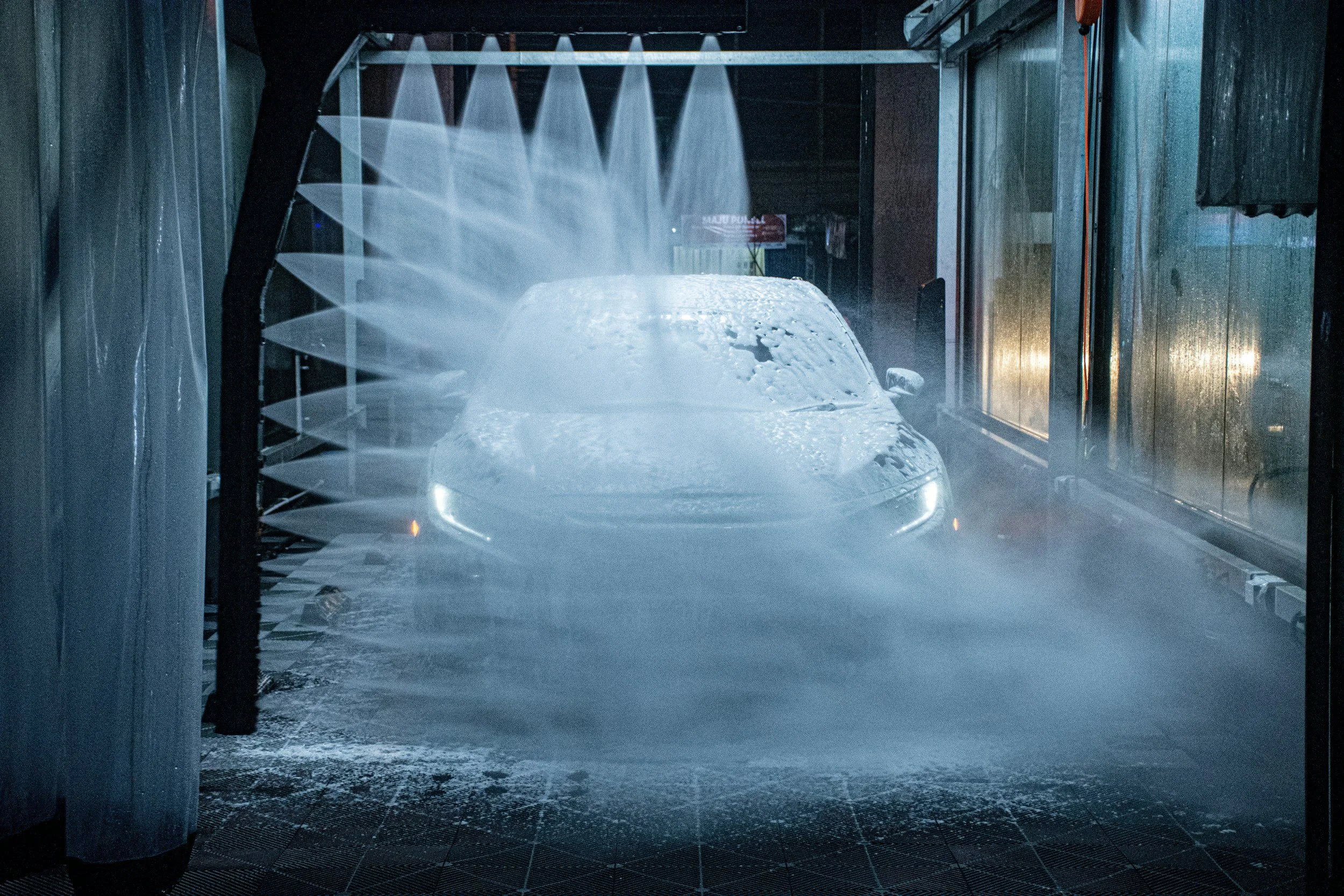 A car in a car wash being washed with high-pressure water spray.