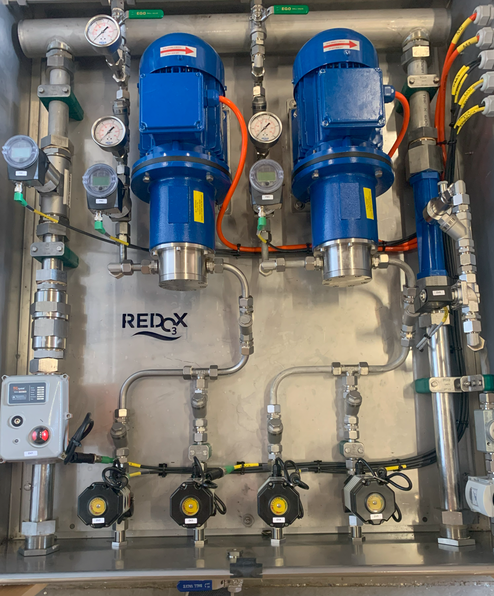 Industrial water treatment equipment with piping, gauges, and control valves, labeled 'REAX'.