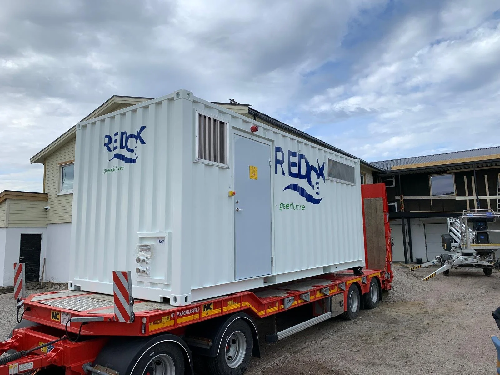 En hvit container på en lastebil, plassert på en byggeplass, med logoen 'REDCX' og teksten 'geerfuture'.