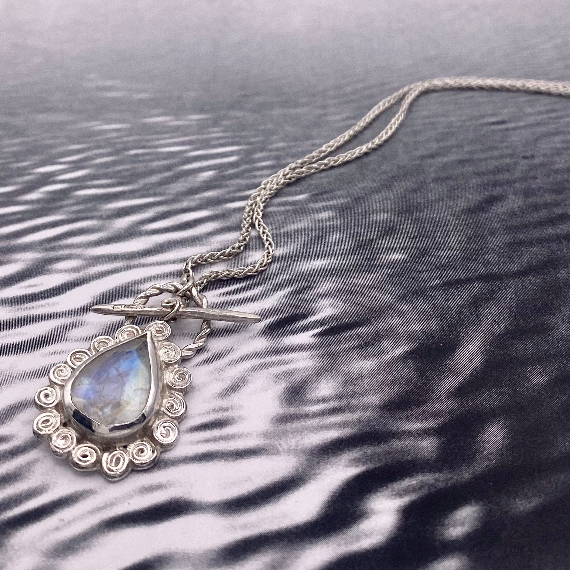 Large Pear Rainbow Moonstone Swirly Halo Pendant on water.jpg