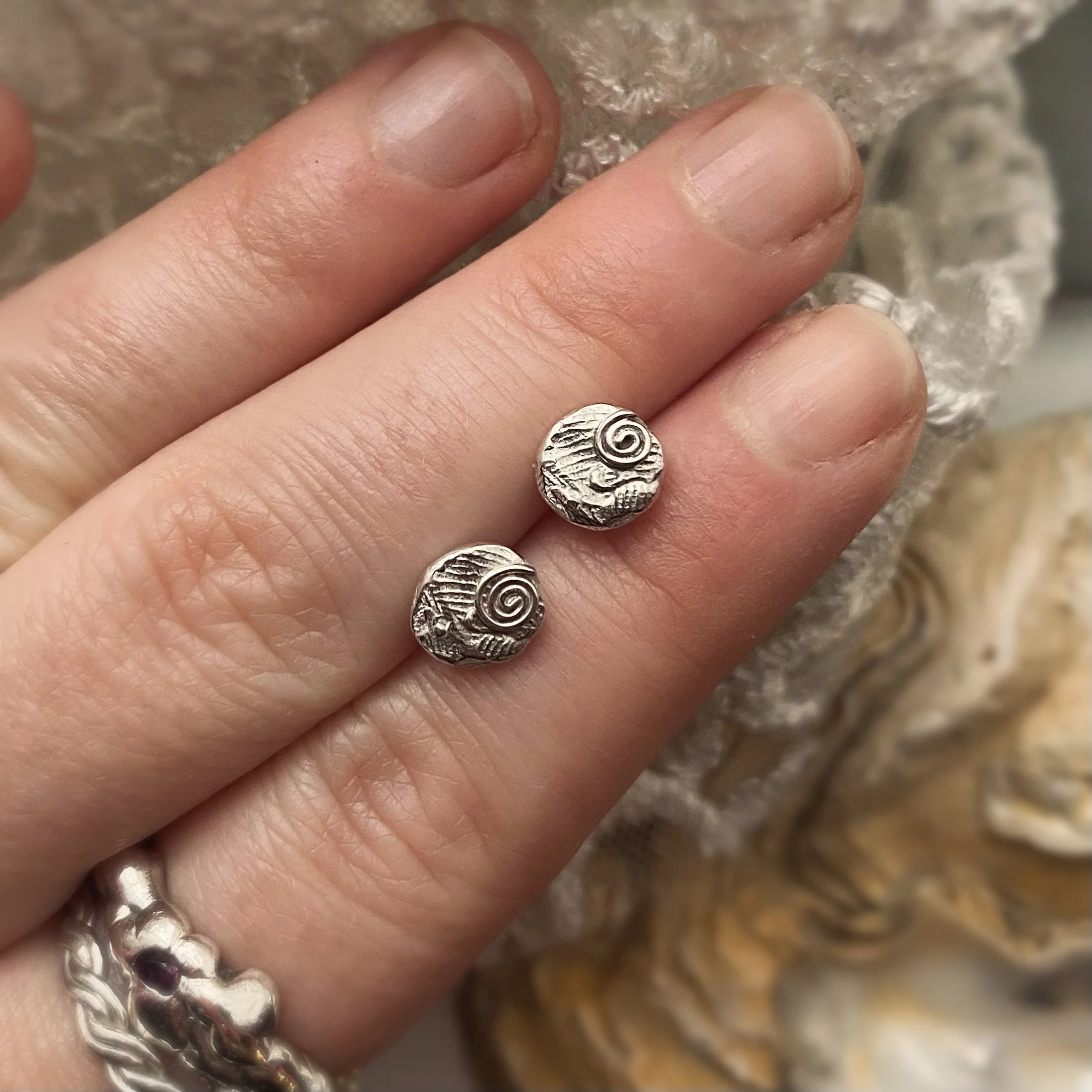 Tiny Silver Swirl Texture Studs on hand.jpg