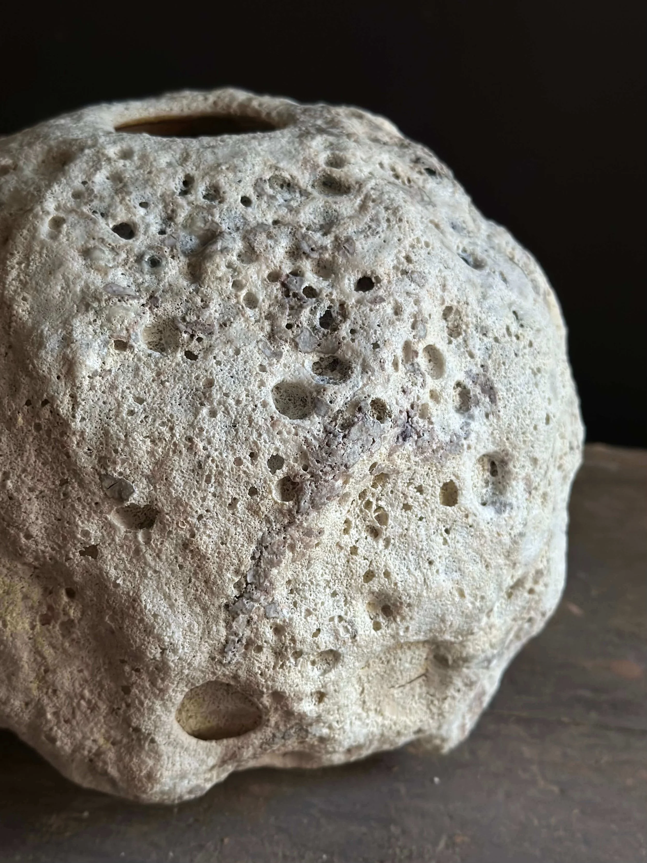 Close-up of porous round vessel with coral/crater lava glaze
