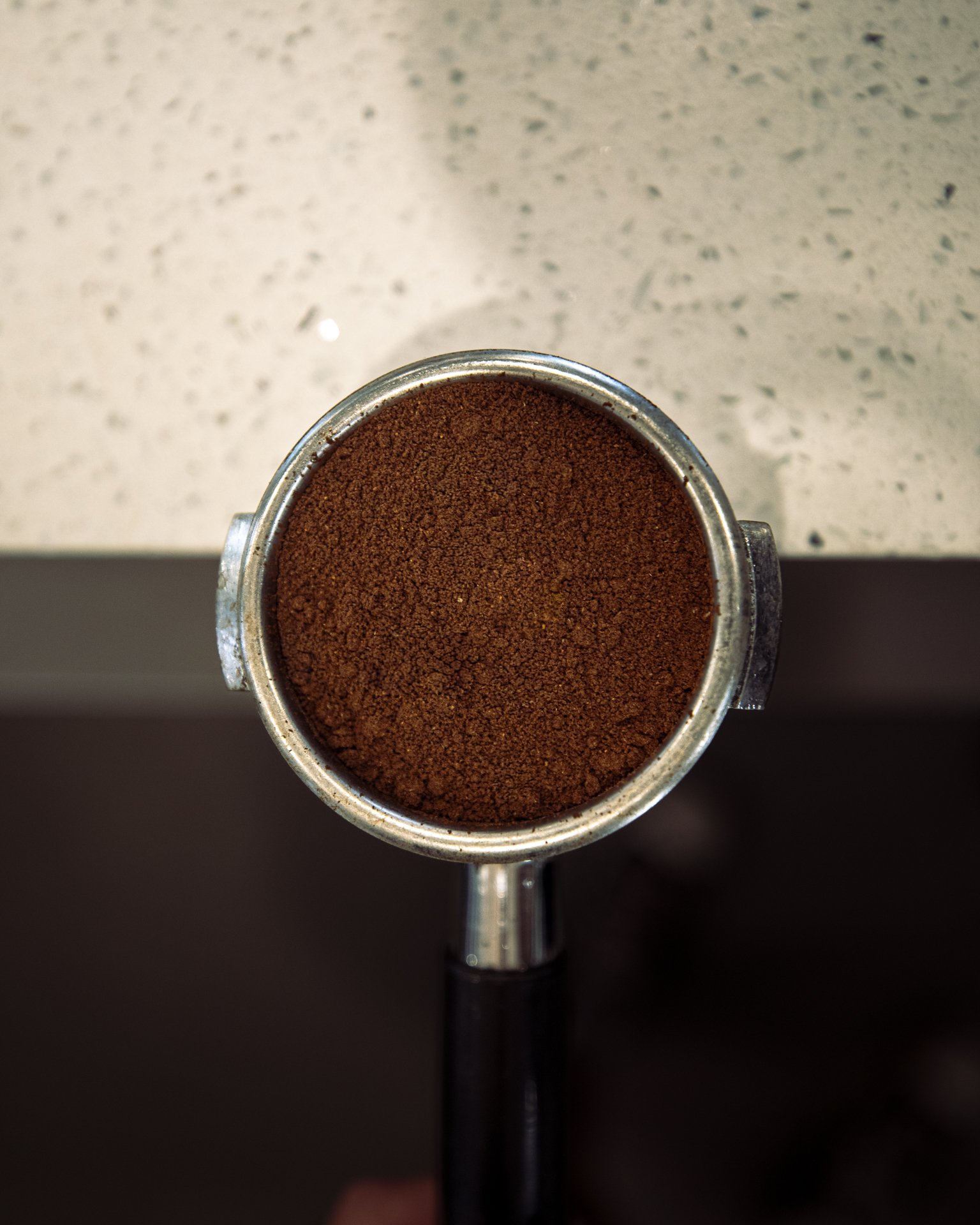 Evenly ground espresso coffee in a portafilter using Seven Miles Coffee beans at a specialty cafe
