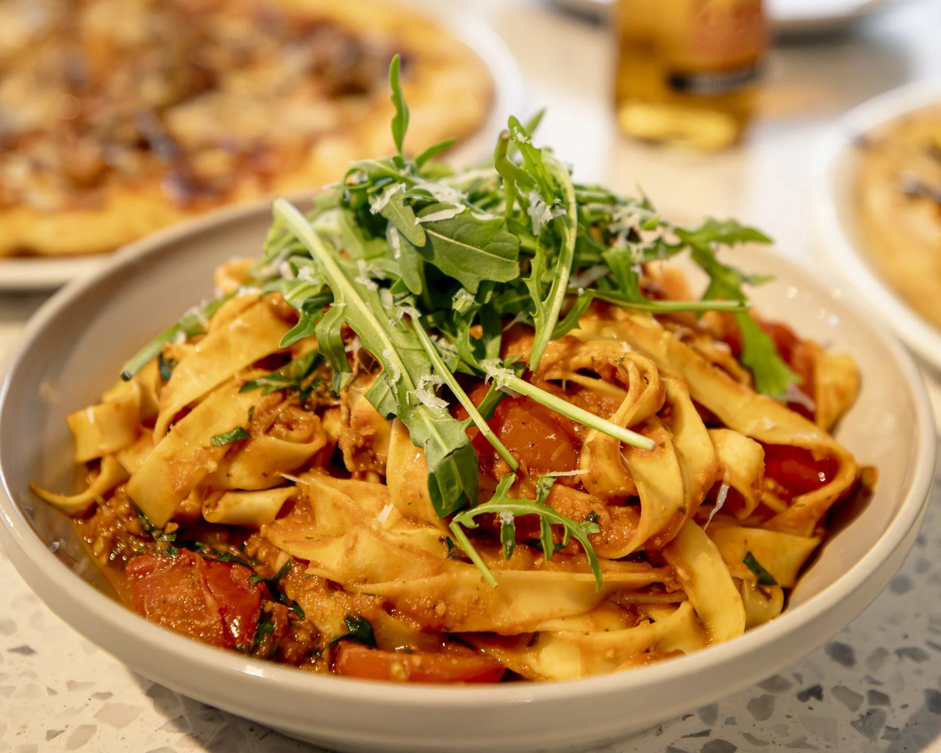 Pasta with tomato sauce topped with arugula and grated cheese