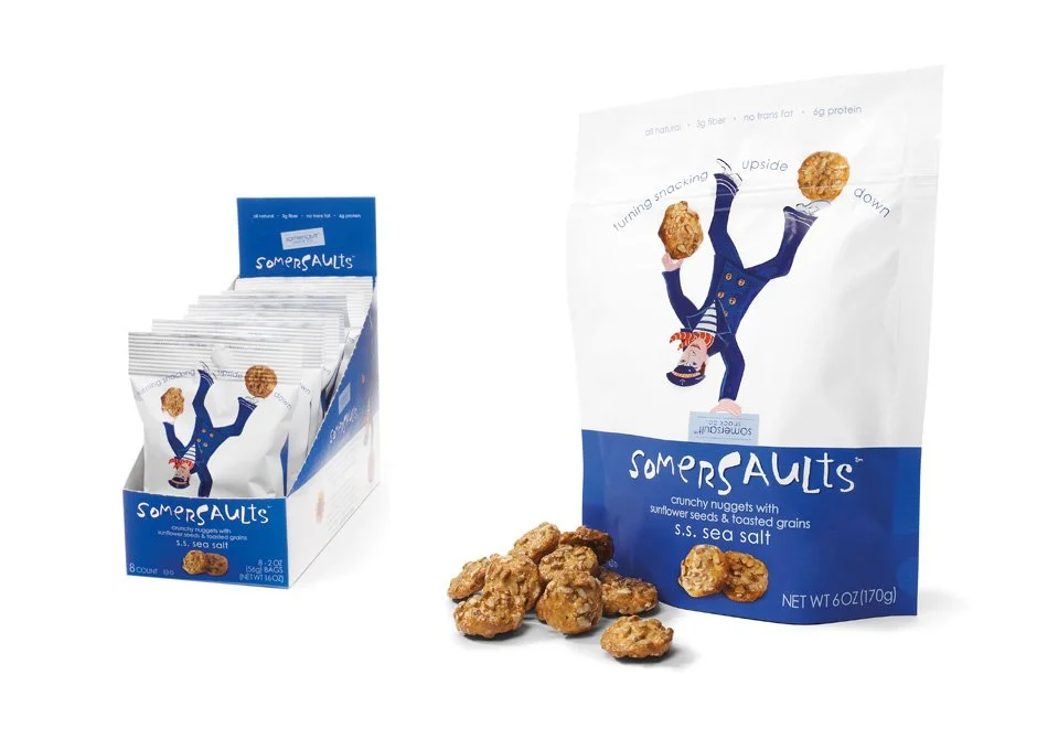 A bag of Somersaults crunchy nuggets with sunflower seeds and toasted grains, labeled 'S.S. sea salt,' with some nuggets spilled in front of the bag and a display box containing multiple smaller bags.