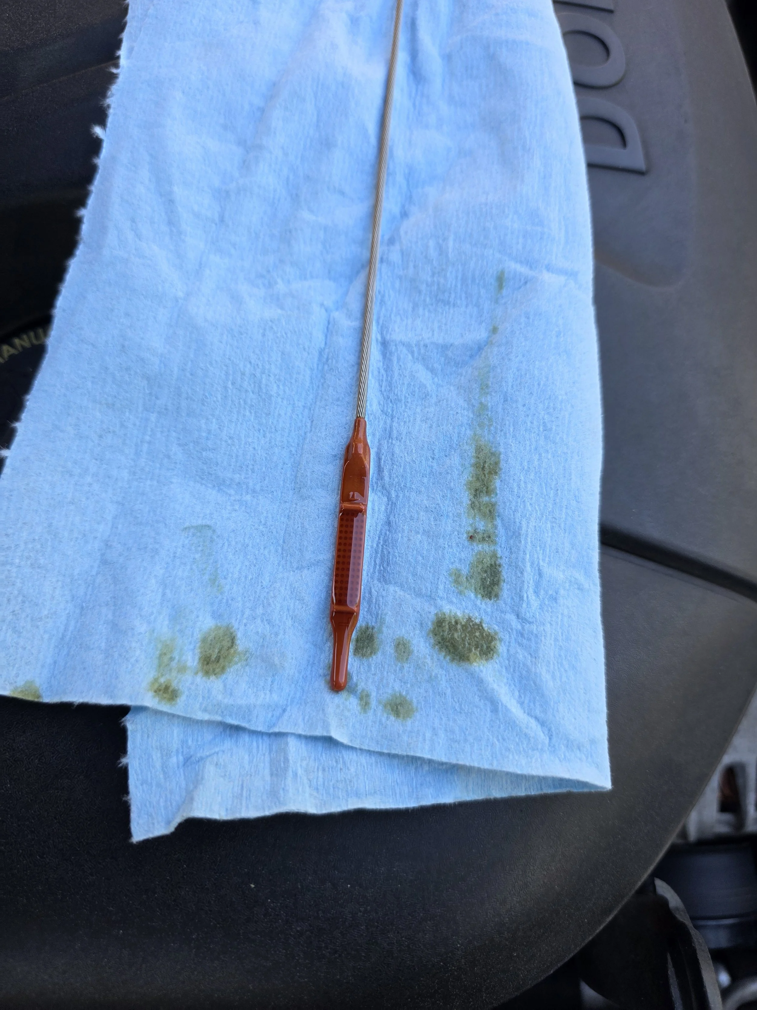 A blue medical gauze pad with greenish bloodstains, with a red blood collection tube on top, placed on a black surface.